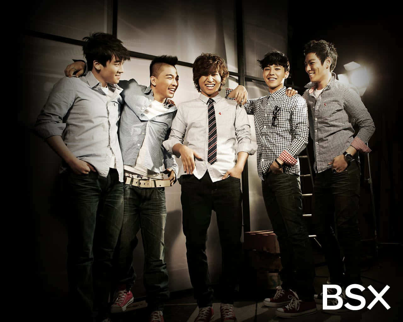 Bigbang 桌布 壁紙 — 五位微笑的年輕男士穿著休閒襯衫和牛仔褲，在深色攝影棚背景下互相搭肩合照。