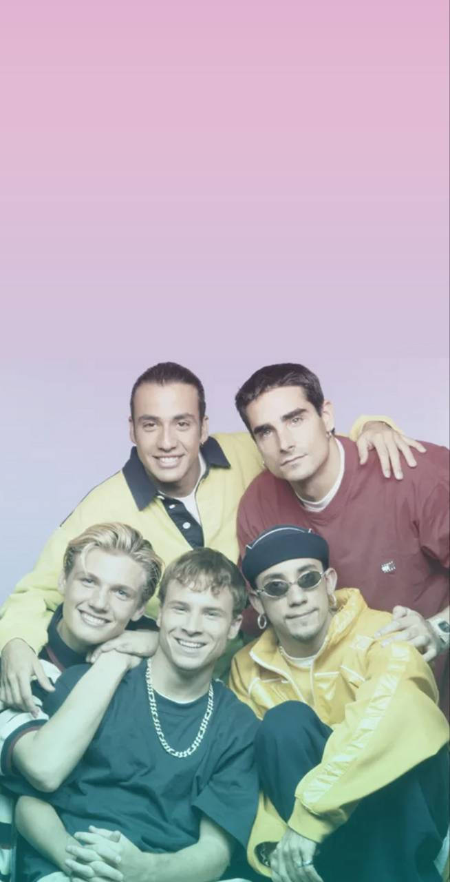 Backstreet 桌布 壁紙 — 五位微笑的年輕男子穿著90年代街頭服飾，在柔和的粉紅到薰衣草漸變背景前一起擺姿勢。