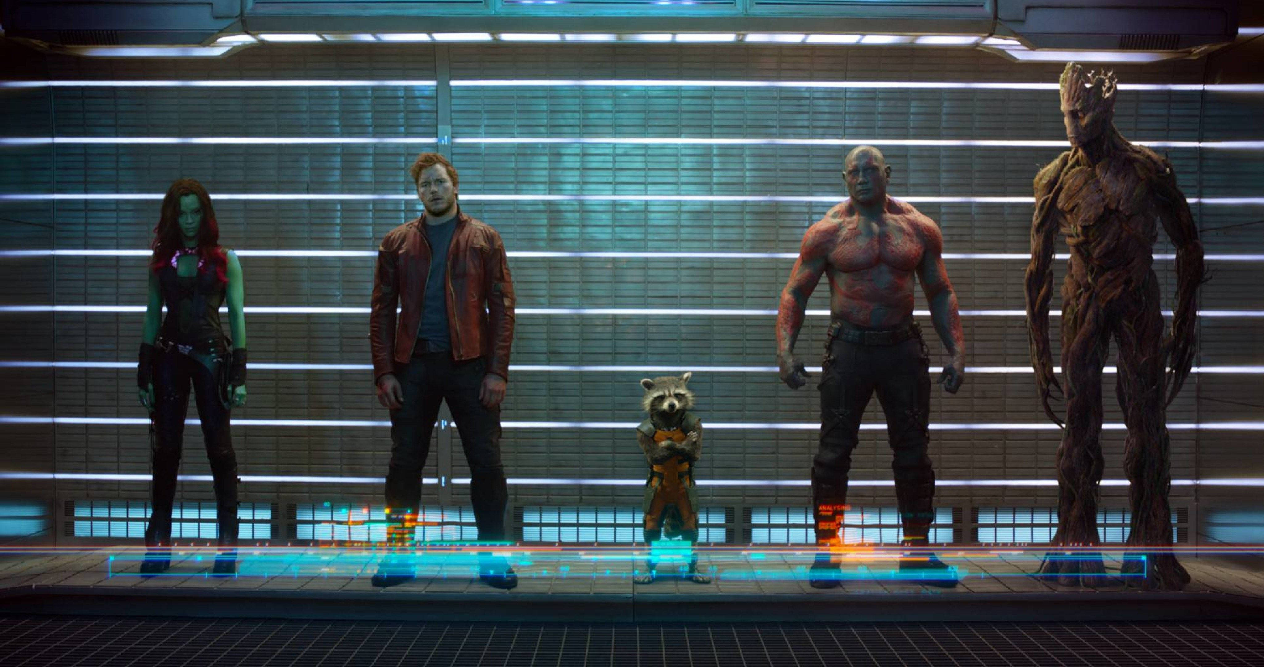 4K Guardians Of The Galaxy 桌布 壁紙 — 五位星際異攻隊站在一個由發光藍色水平燈光照亮的未來太空船走廊中。