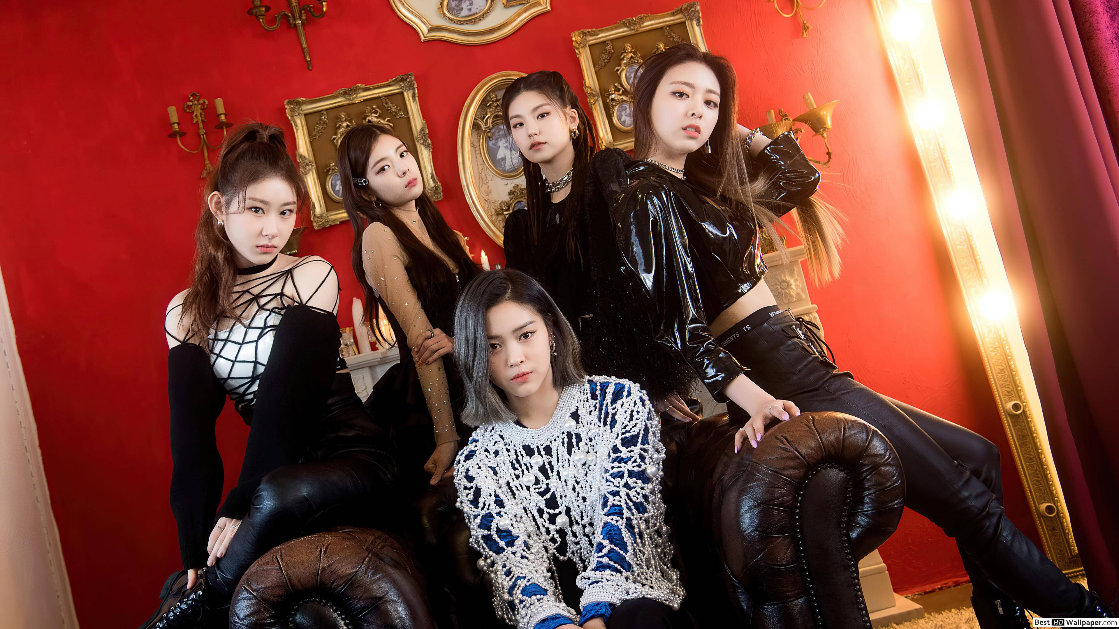 ITZY 桌布 壁紙 — 五位時尚女性自信地坐在皮革沙發上，背景是鮮紅色的牆壁，裝飾著金色邊框的鏡子和燭台。