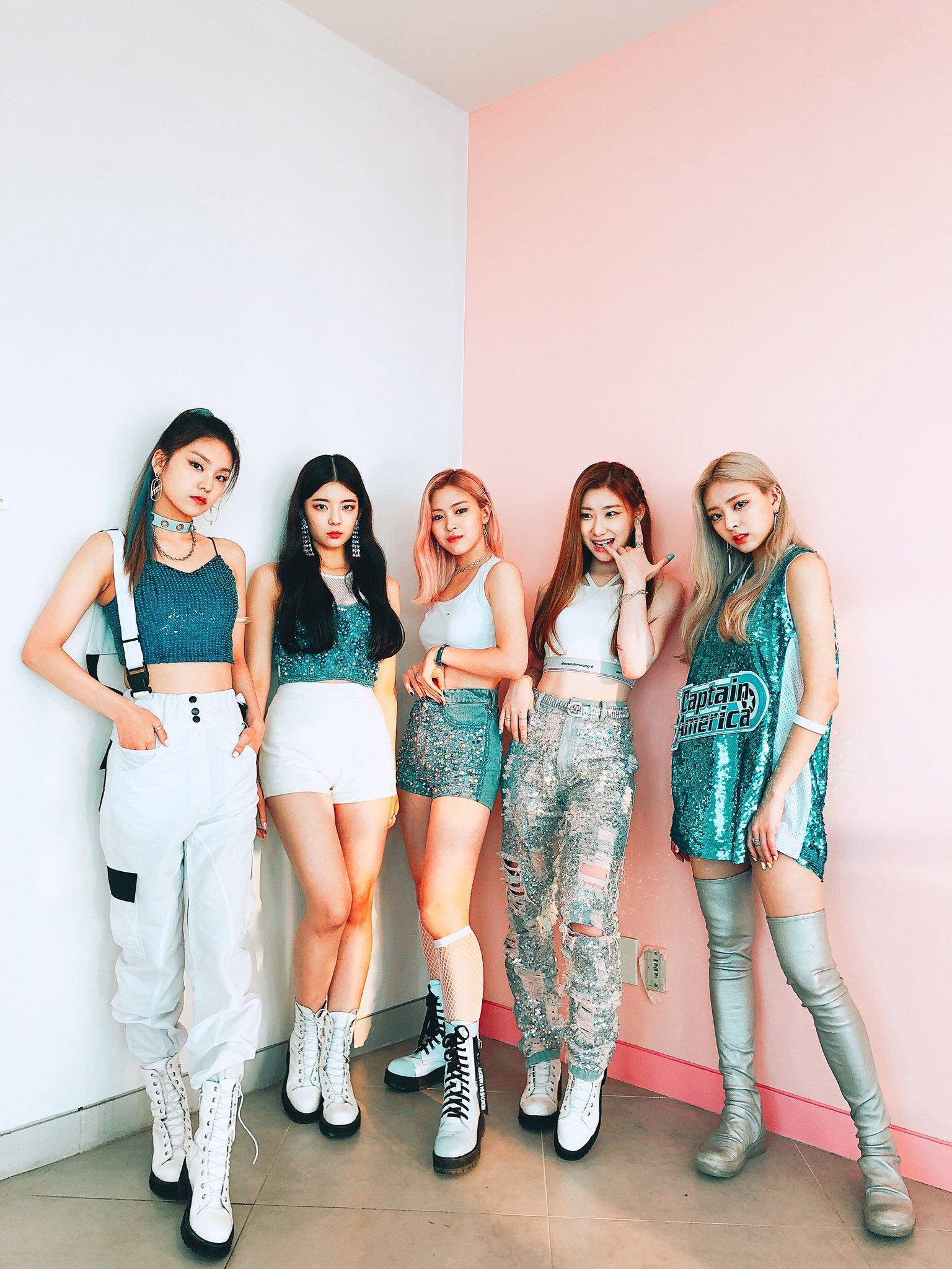 ITZY 桌布 壁紙 — 五位時尚年輕女性穿著潮流服裝，在光線明亮的室內空間中，自信地以粉紅和白色牆壁為背景擺姿勢。