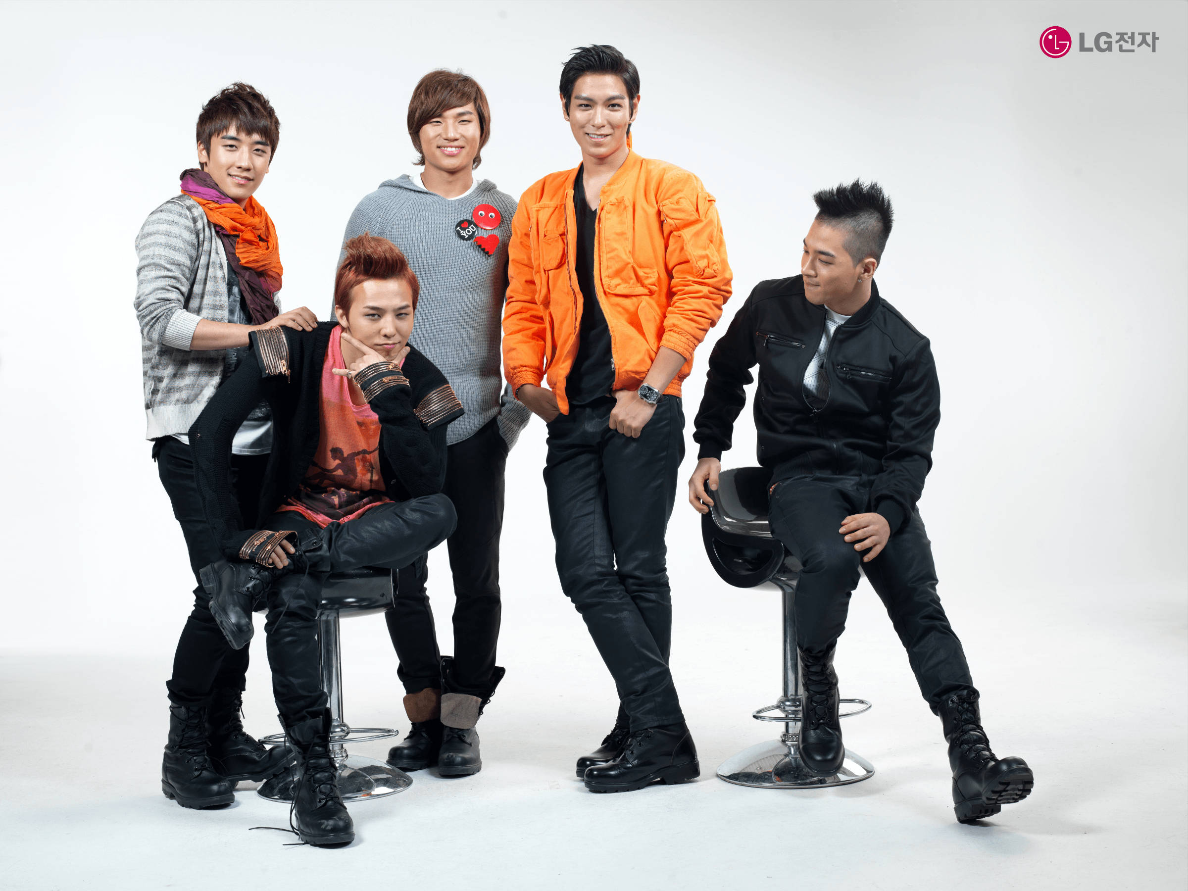 Bigbang 桌布 壁紙 — 五位時尚年輕男士在白色背景前，穿著鮮豔的橙色和黑色服裝，自信地在攝影棚中擺姿勢。
