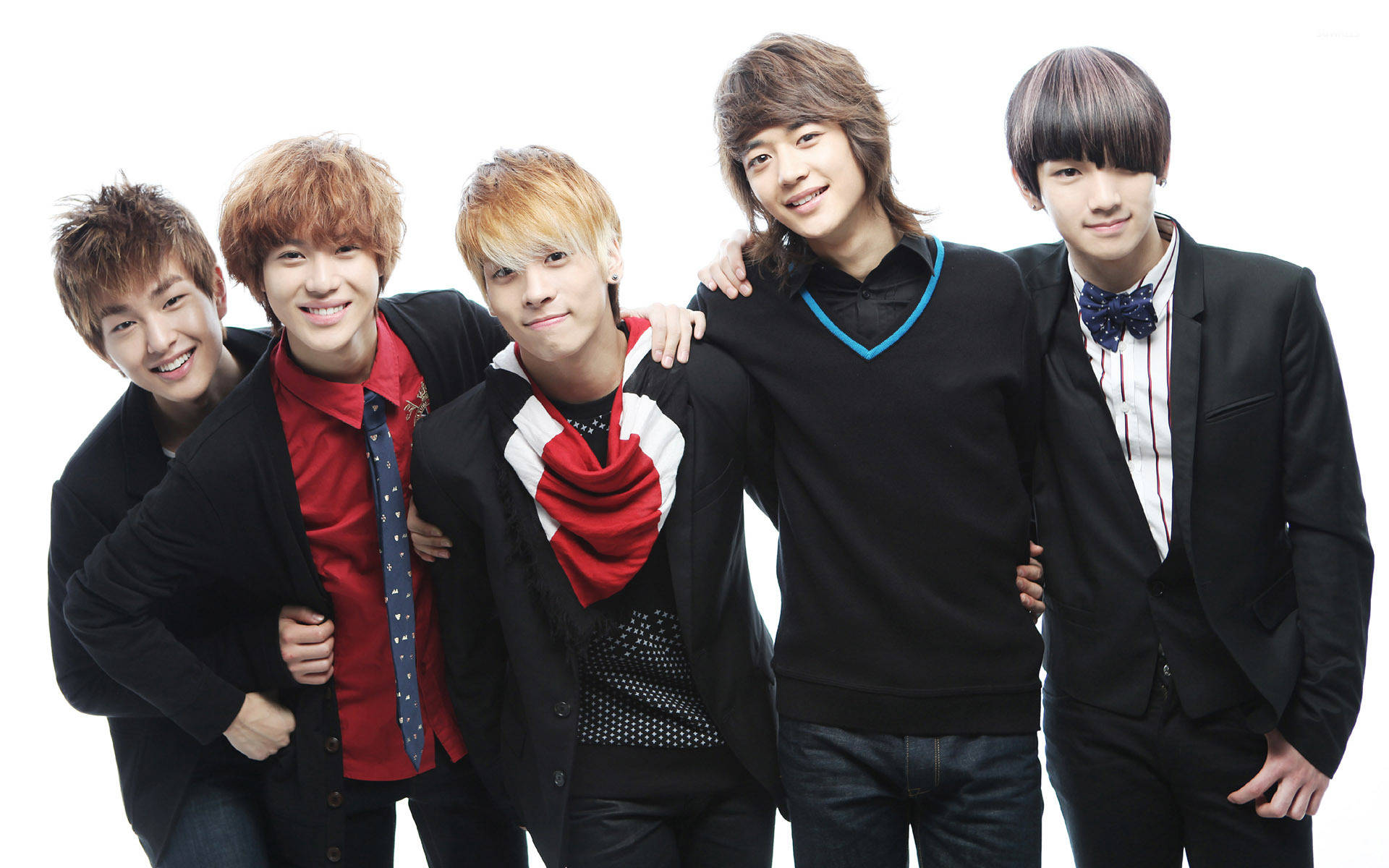 Shinee 桌布 壁紙 — 五位時尚年輕男子身穿黑色外套與彩色點綴，在純白背景前緊密擺姿勢，展現自信笑容。