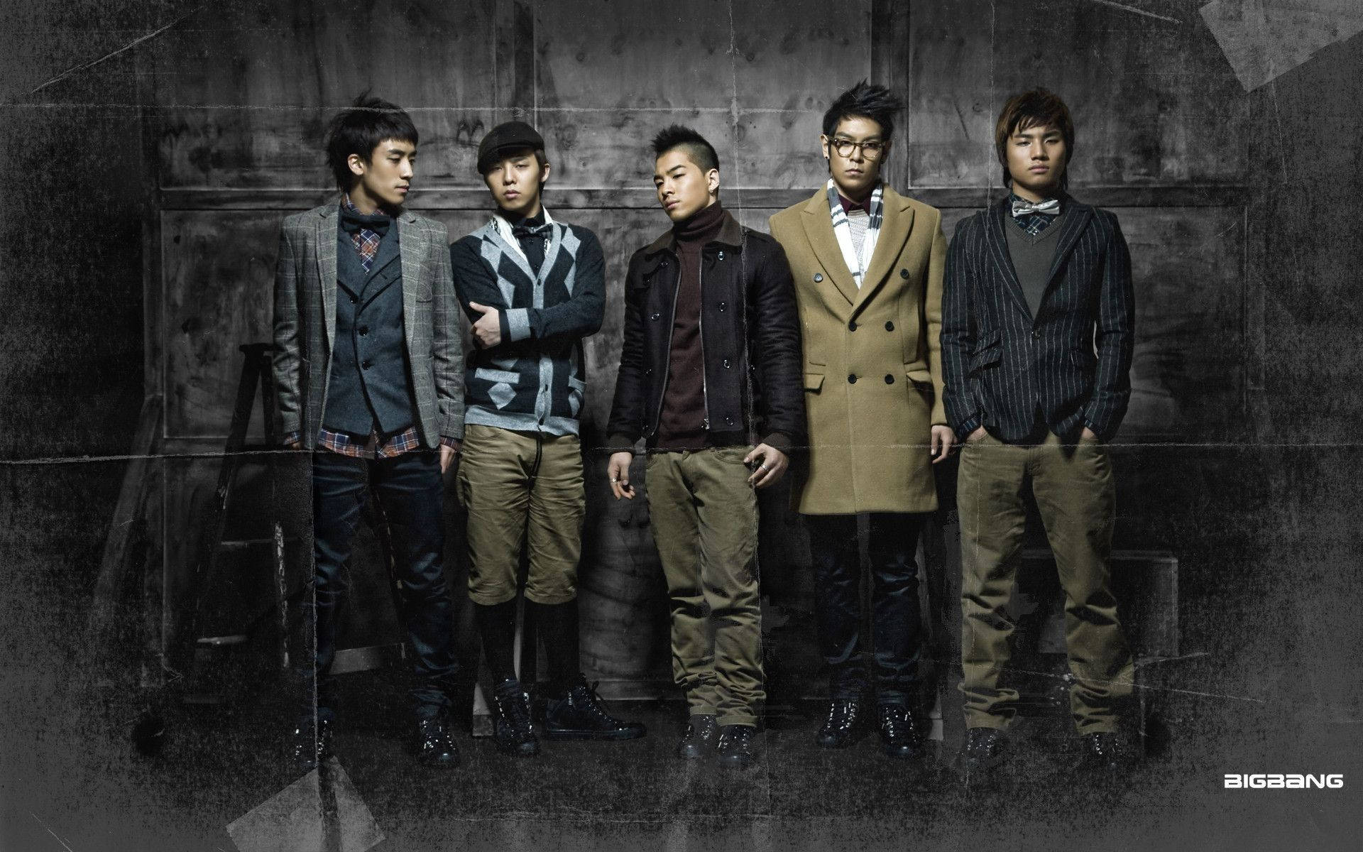 Bigbang 桌布 壁紙 — 五位時尚男士身穿訂製大衣和領結，在戲劇性燈光下自信地擺姿勢，背景是粗糙的紋理牆壁。