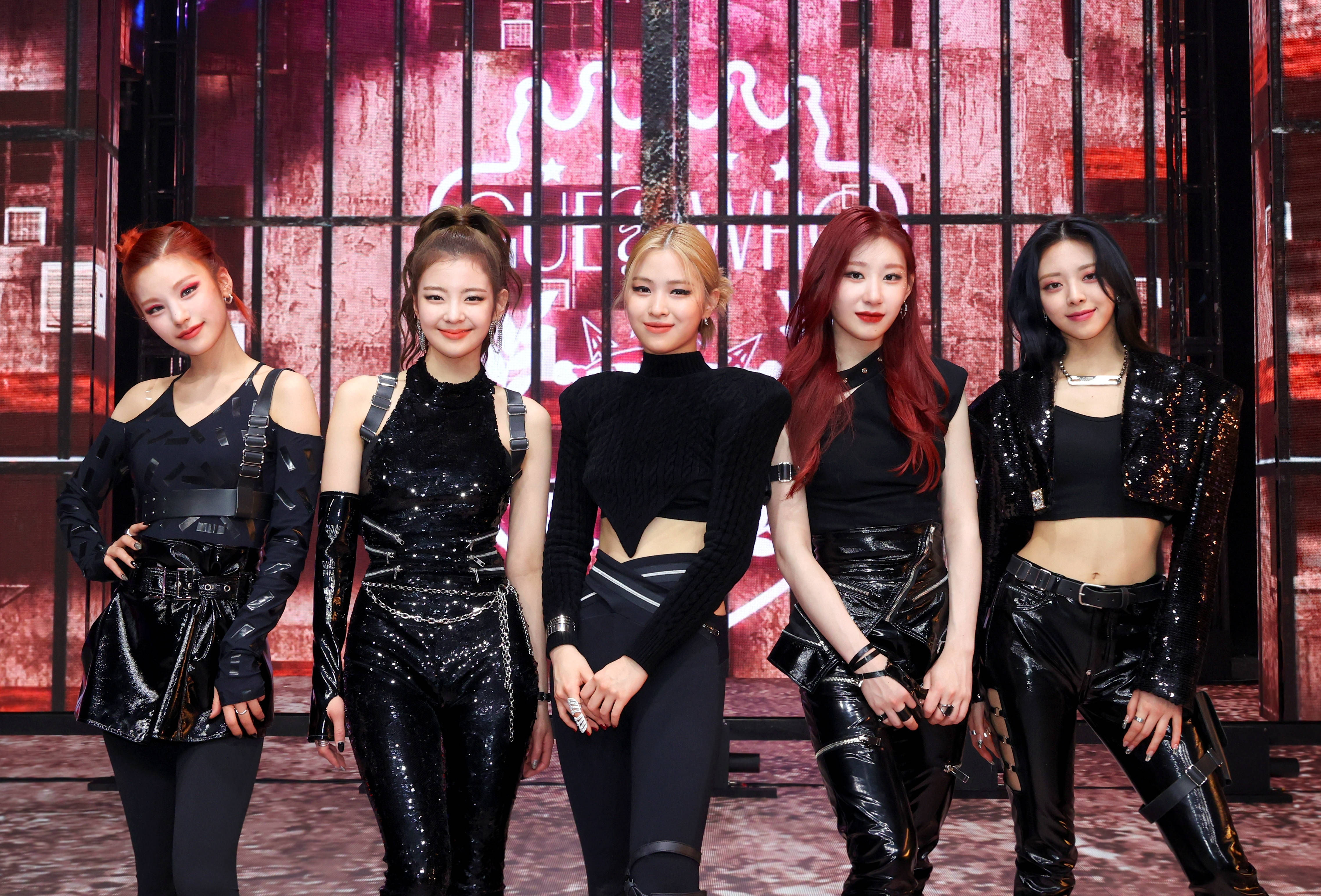 ITZY 桌布 壁紙 — 五位時尚的女表演者穿著黑色亮片服裝，在紅色霓虹燈照亮的城市背景下自信地擺姿勢。