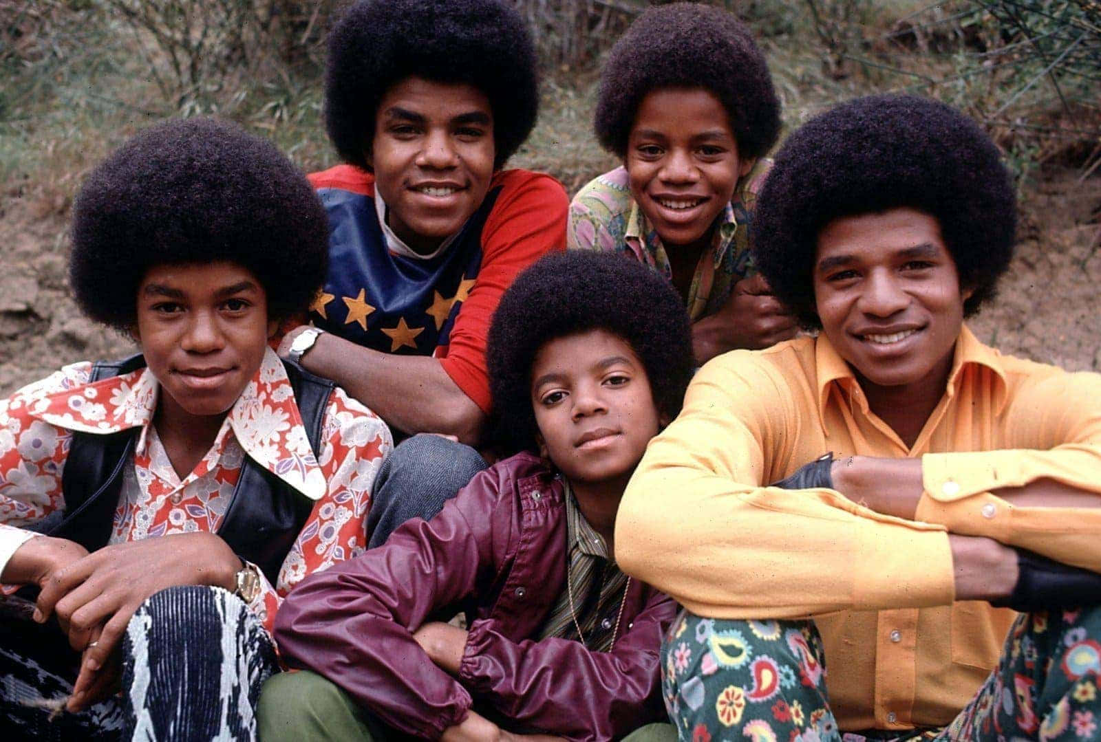 Young Michael Jackson 桌布 壁紙 — 五位留著非洲式髮型的年輕男性，身穿色彩繽紛的1970年代圖案服裝，在戶外愉快地擺姿勢。