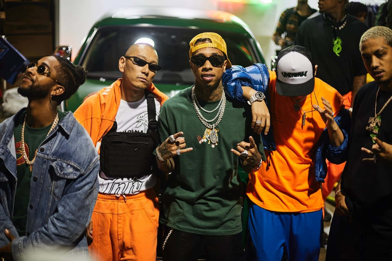 hiphop 桌布 壁紙 — 五位穿著大膽街頭服飾的時尚男士在人造夜間燈光下自信地在綠色汽車旁擺姿勢。