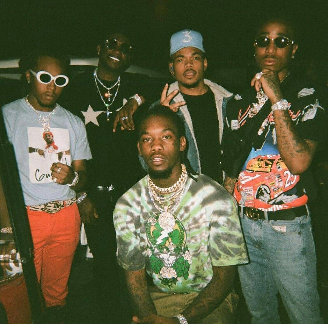 90s Rapper 桌布 壁紙 — 五位穿著時尚的男士在昏暗的燈光下自信地擺姿勢，佩戴著大膽的珠寶和色彩繽紛的街頭服飾。