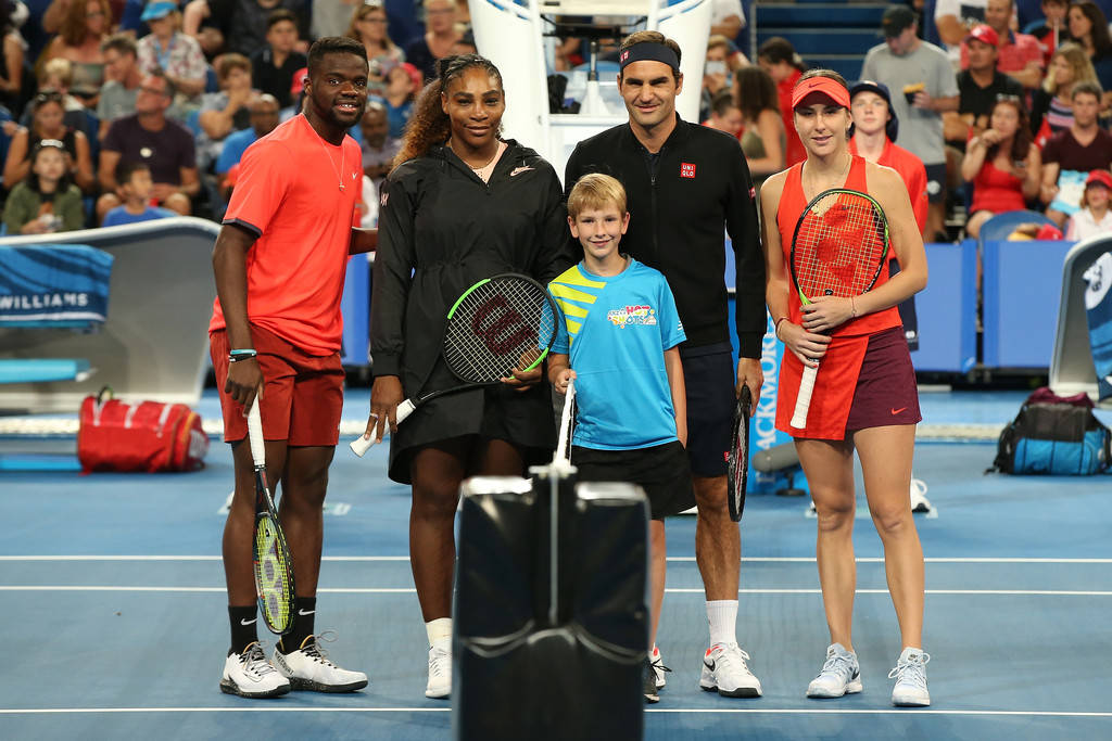 Tennis 桌布 壁紙 — 五位網球明星和一個小男孩在藍色硬地球場上一起擺姿勢，背景有觀眾。