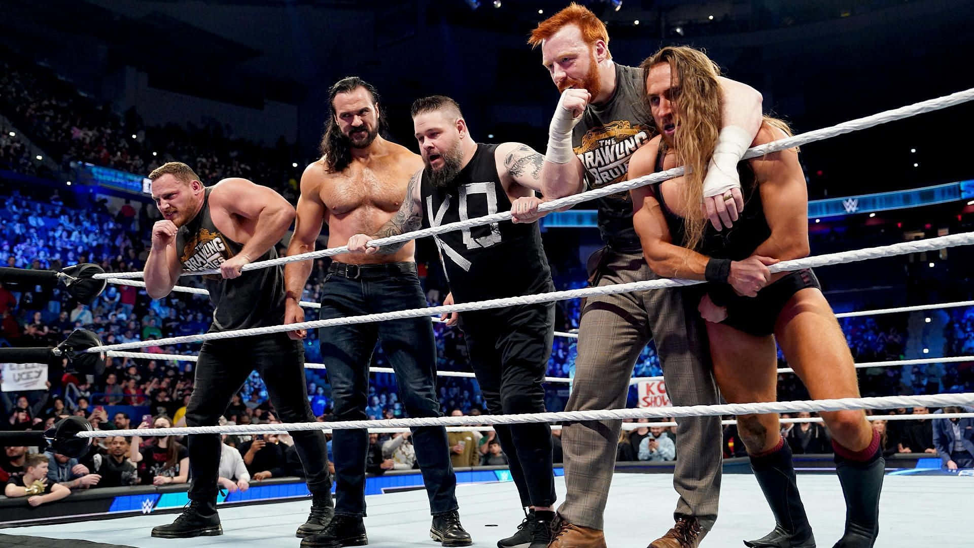 WWE 桌布 壁紙 — 五位肌肉發達的摔角手在擠滿觀眾的場館中，於一場激烈的WWE比賽中用力拉著繩索。