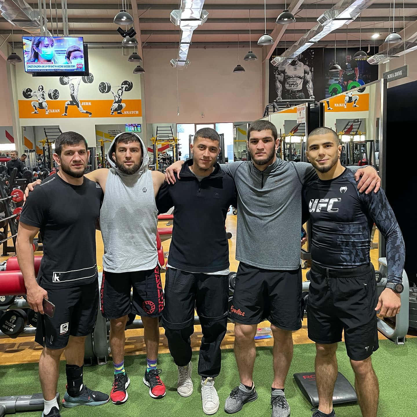 UFC 桌布 壁紙 — 五位肌肉發達的男子穿著健身服飾，在設備齊全的健身中心互相搭肩合照。