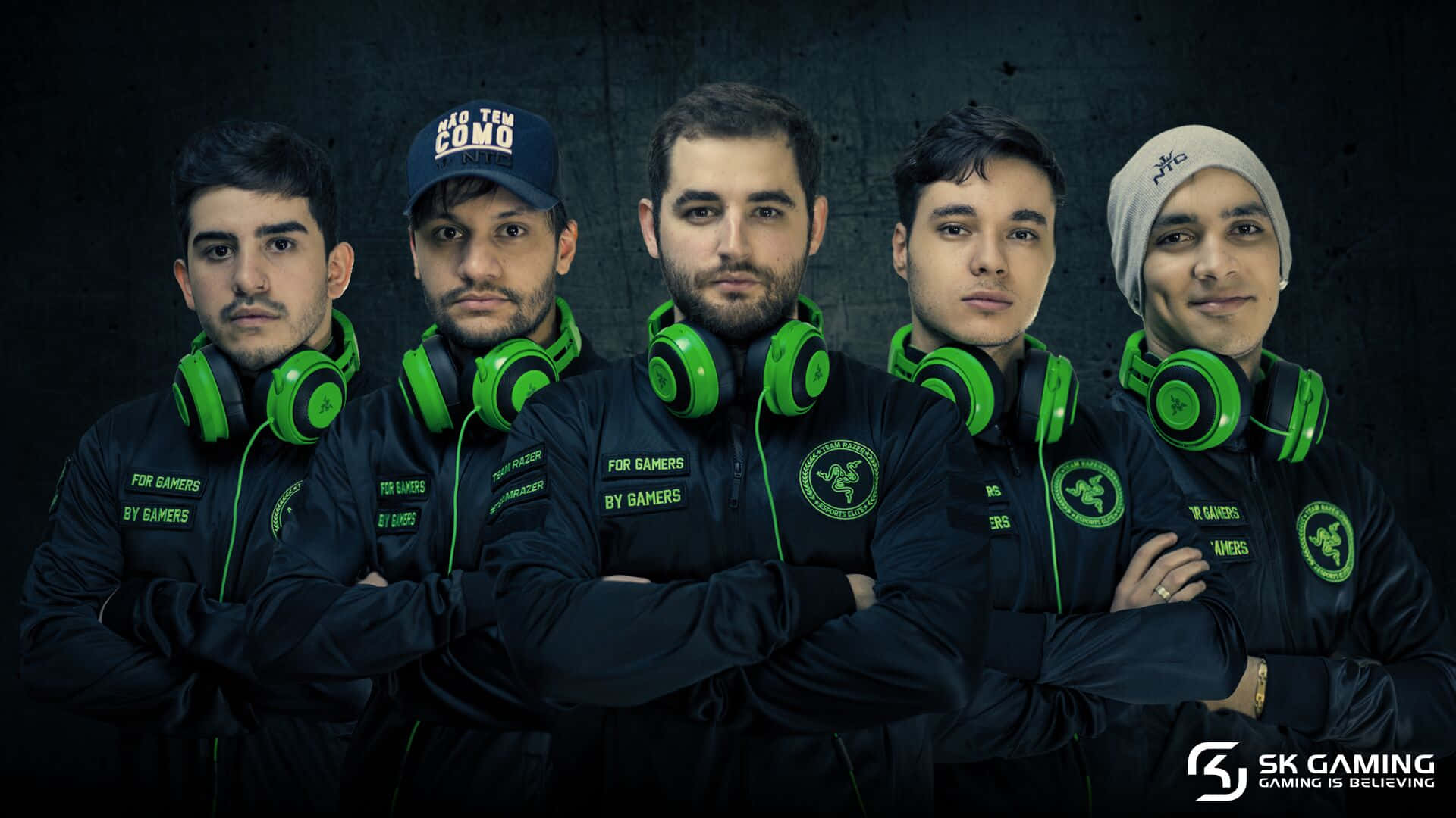 Sk Gaming 桌布 壁紙 — 五位自信的電競運動員身穿黑色外套和亮綠色Razer耳機，在深色紋理牆前擺姿勢。