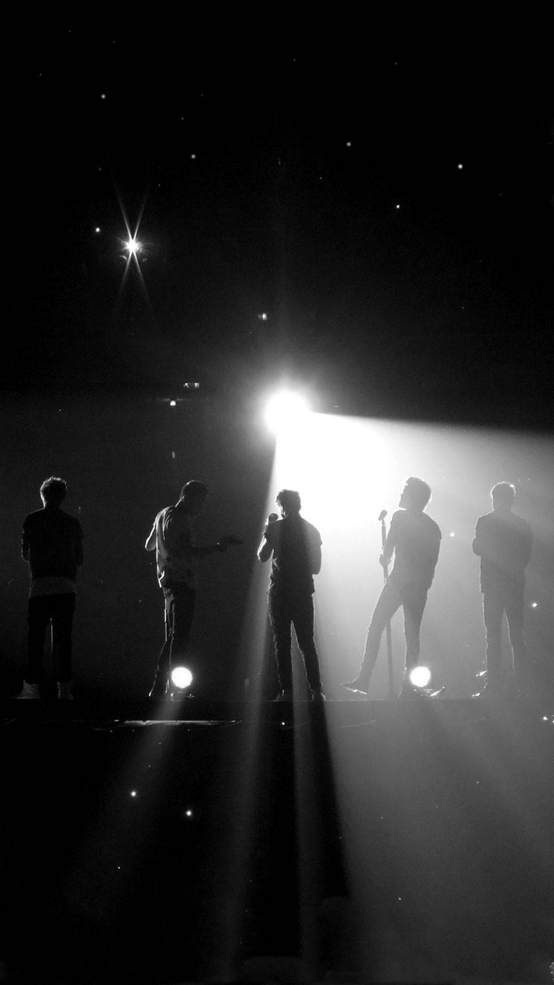 One Direction Aesthetic 桌布 壁紙 — 五位表演者以剪影形式站在漆黑的舞台上，沐浴在戲劇性的聚光燈和星形舞台燈光中。