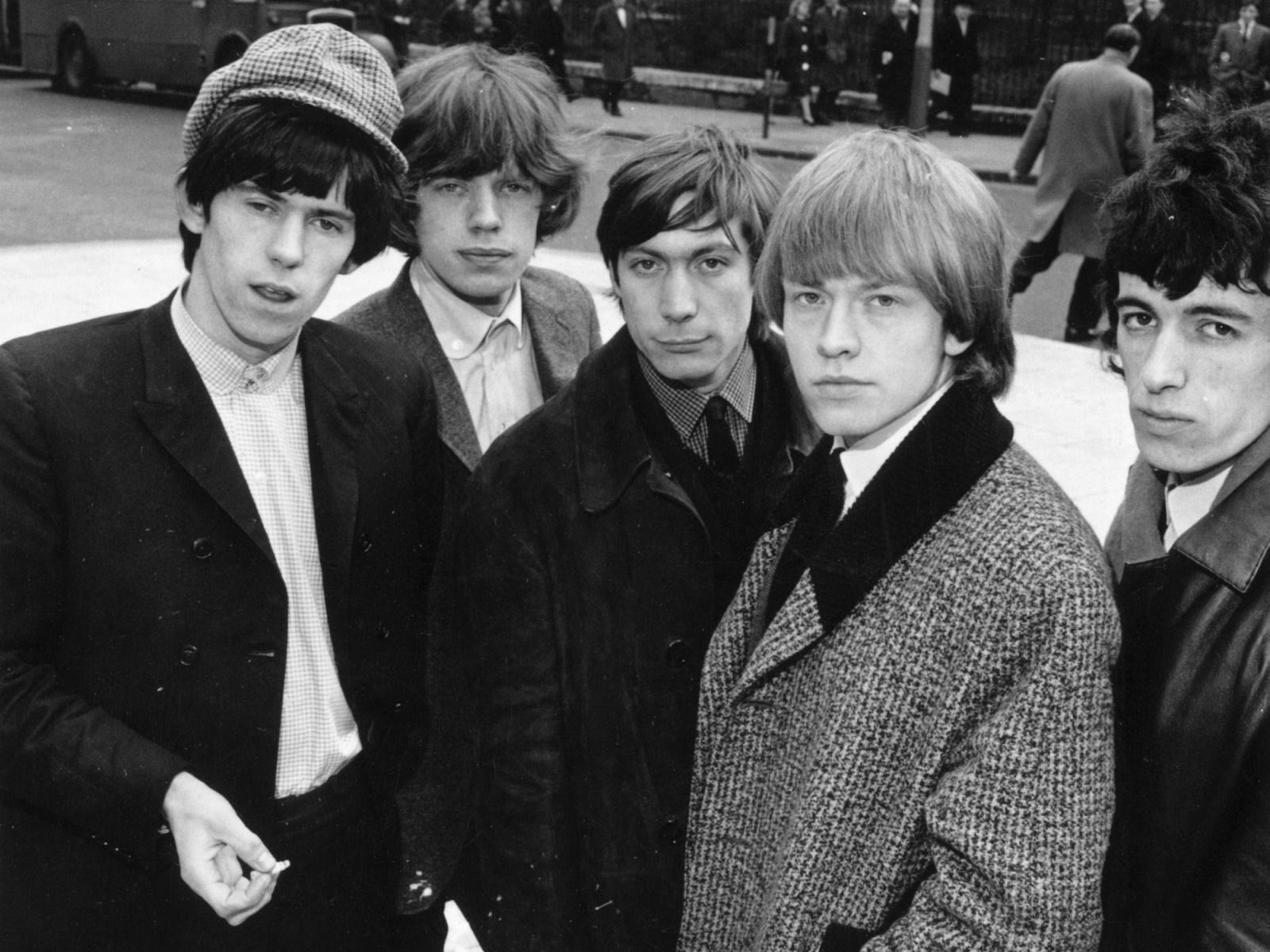 Rock 桌布 壁紙 — 五位身穿1960年代大衣和帽子的年輕男子，在經典黑白照片中一起站在城市街道上。