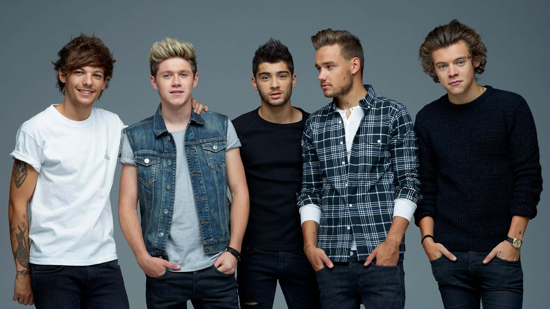 One Direction 桌布 壁紙 — 五位身穿休閒服的年輕男子在純灰色攝影棚背景前自信地擺姿勢。
