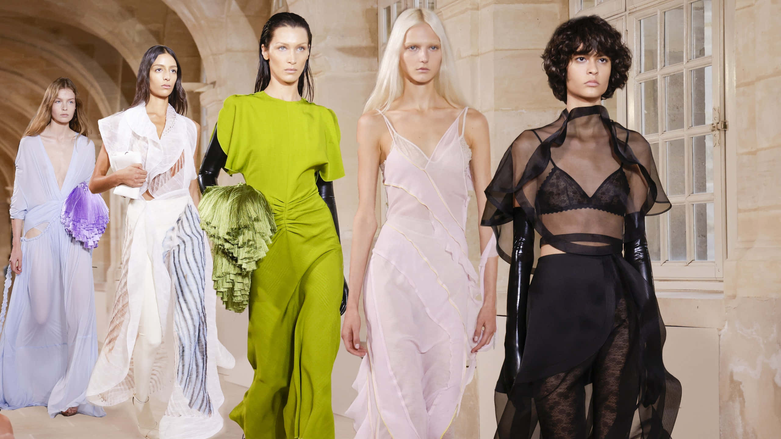 Beautiful Fashion 桌布 壁紙 — 五位身穿前衛時尚的模特兒自信地走過陽光普照的石拱門，穿著大膽的色彩和透明布料。