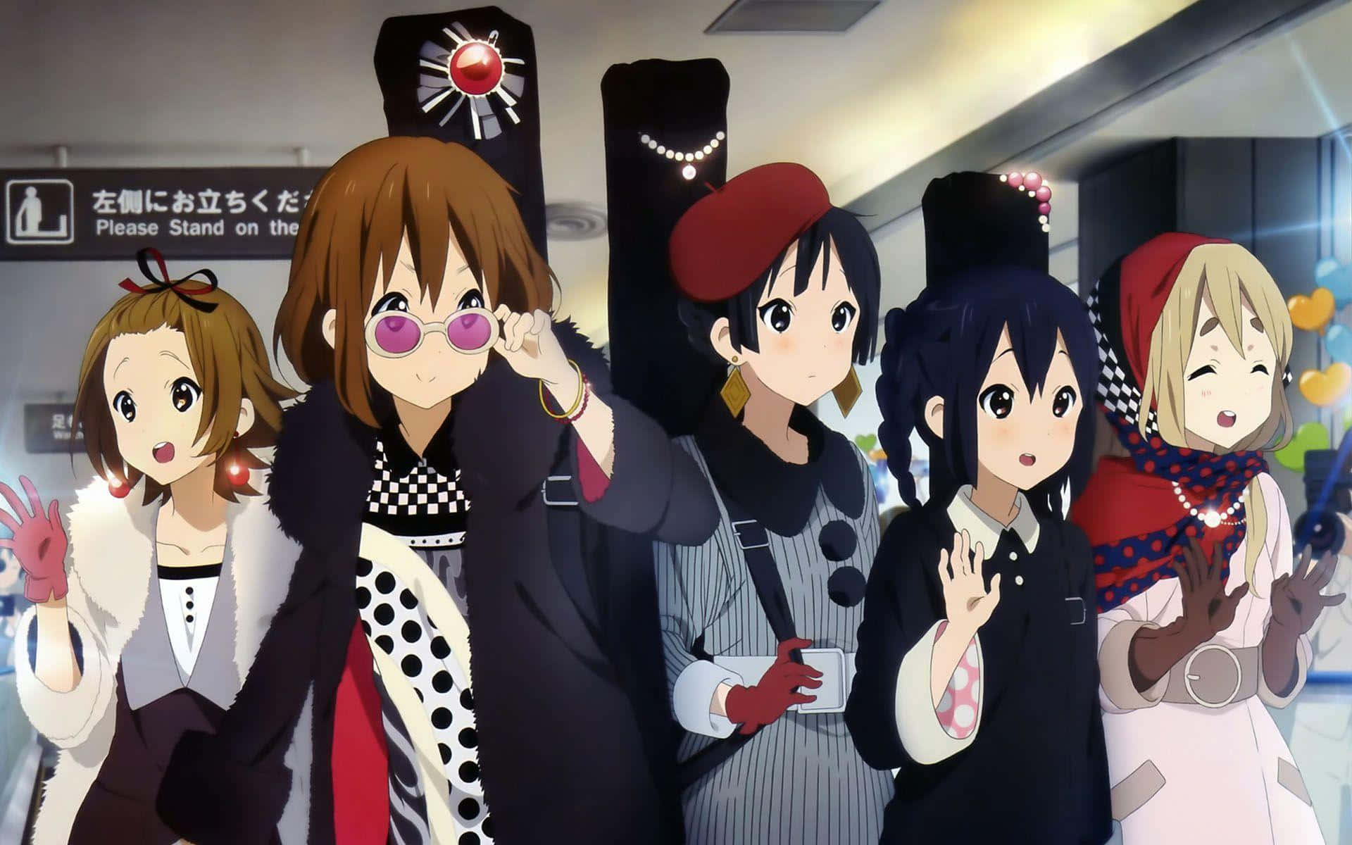 K-ON！輕音部 桌布 壁紙 — 五位身穿時尚服裝的動漫女孩在光線明亮的室內車站（帶有日語標牌）中愉快地揮手。