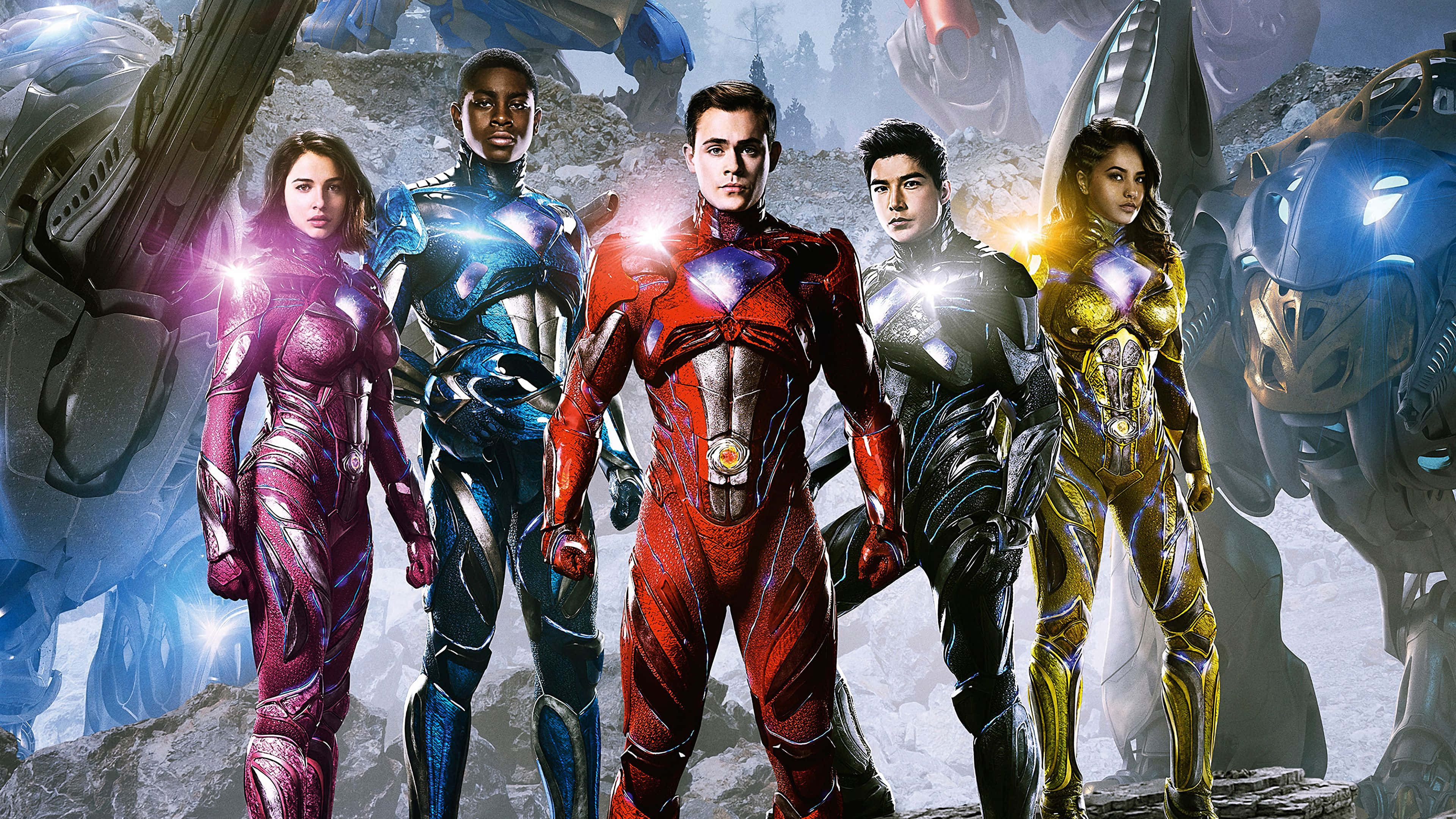 金剛戰士 桌布 壁紙 — 五位身穿發光金屬套裝的超級英雄，在巨型機械戰士和破碎石塊的背景下英勇站立。