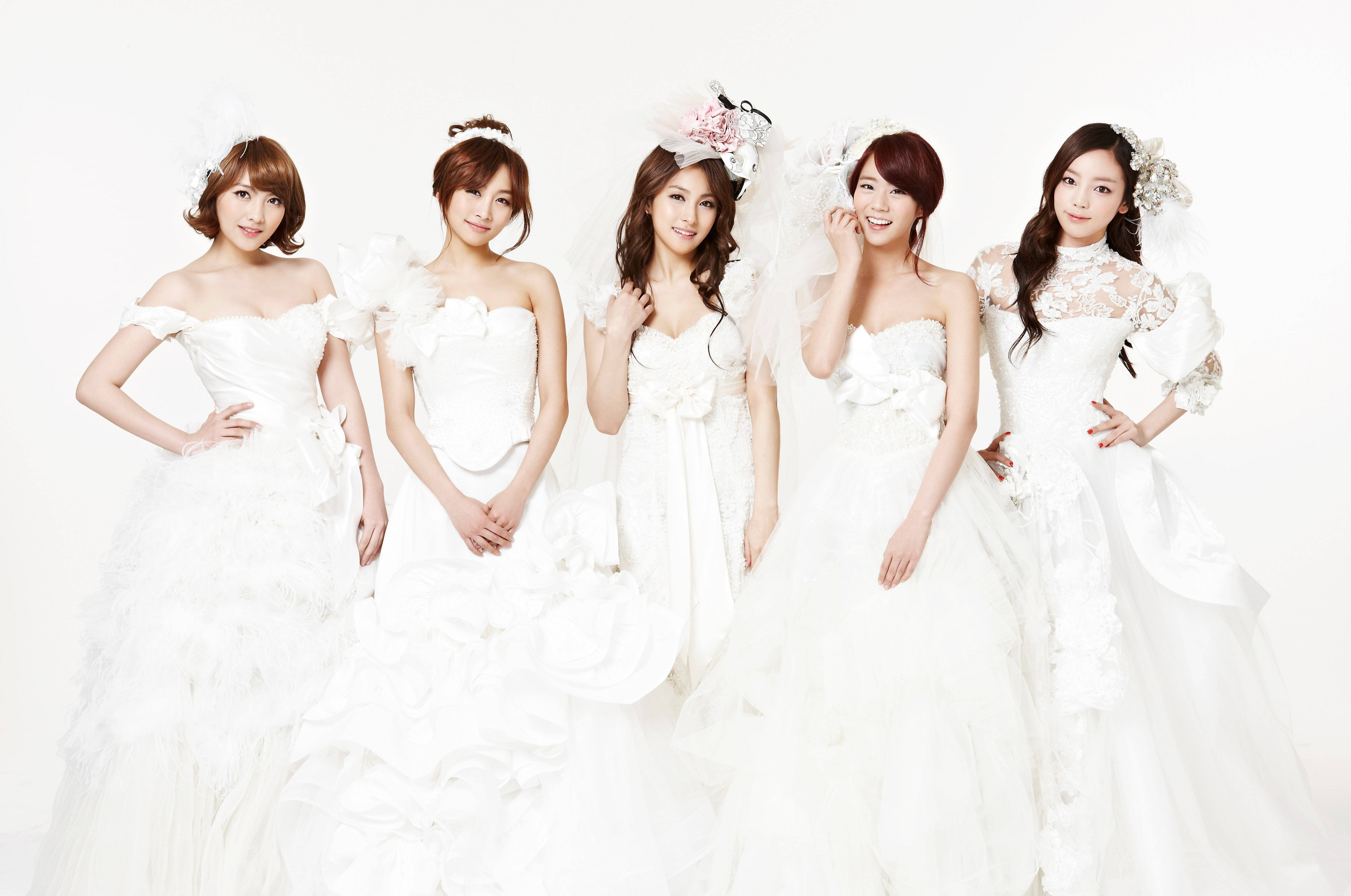 Wedding Dress 桌布 壁紙 — 五位身穿精緻白色婚紗的女性在柔和的燈光下，在純白色背景前優雅地擺姿勢。