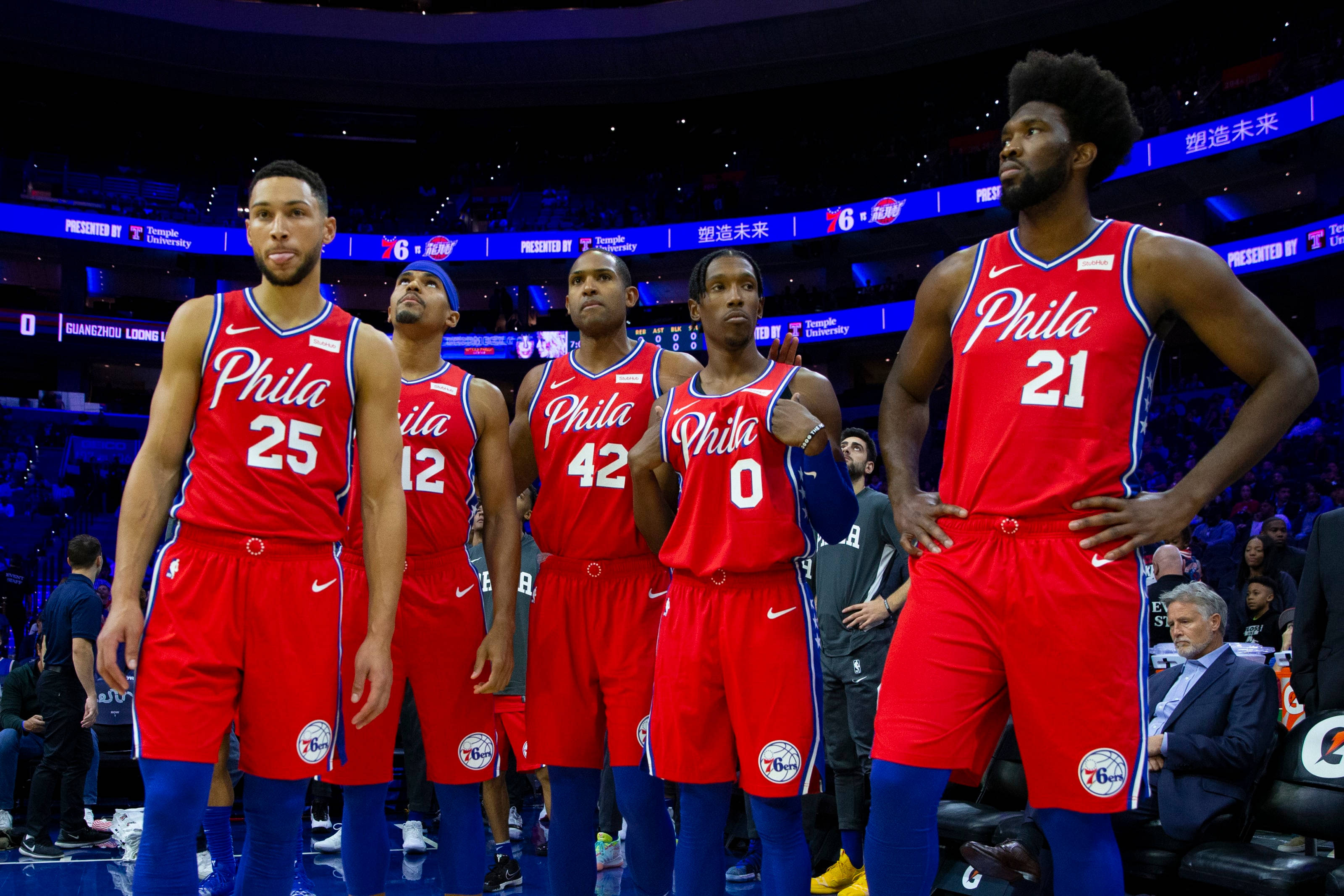 76ers 桌布 壁紙 — 五位身穿紅色球衣的費城76人籃球運動員在比賽期間自信地站在燈光明亮的球場上。