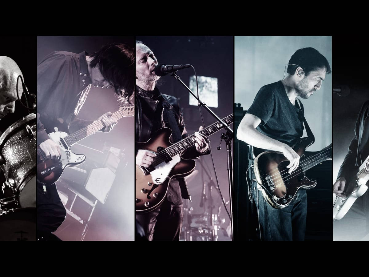 band 桌布 壁紙 — 五位音樂家在戲劇性的舞台燈光下，用吉他和鼓進行激烈的現場表演。