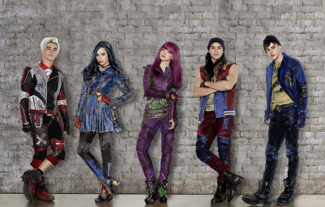 Disney Descendants 桌布 壁紙 — 五位風格化的青少年穿著前衛的龐克服裝，在風化的磚牆前自信地擺姿勢。