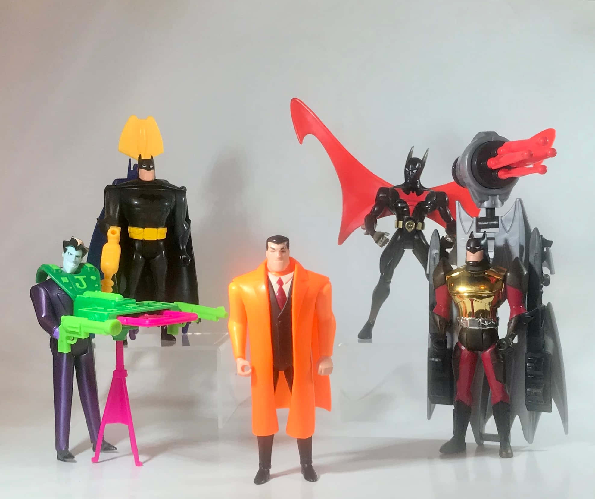 Batman Beyond Return Of The Joker 桌布 壁紙 — 五個不同服裝和姿勢的蝙蝠俠人偶站在透明支架上，背景為純白色。