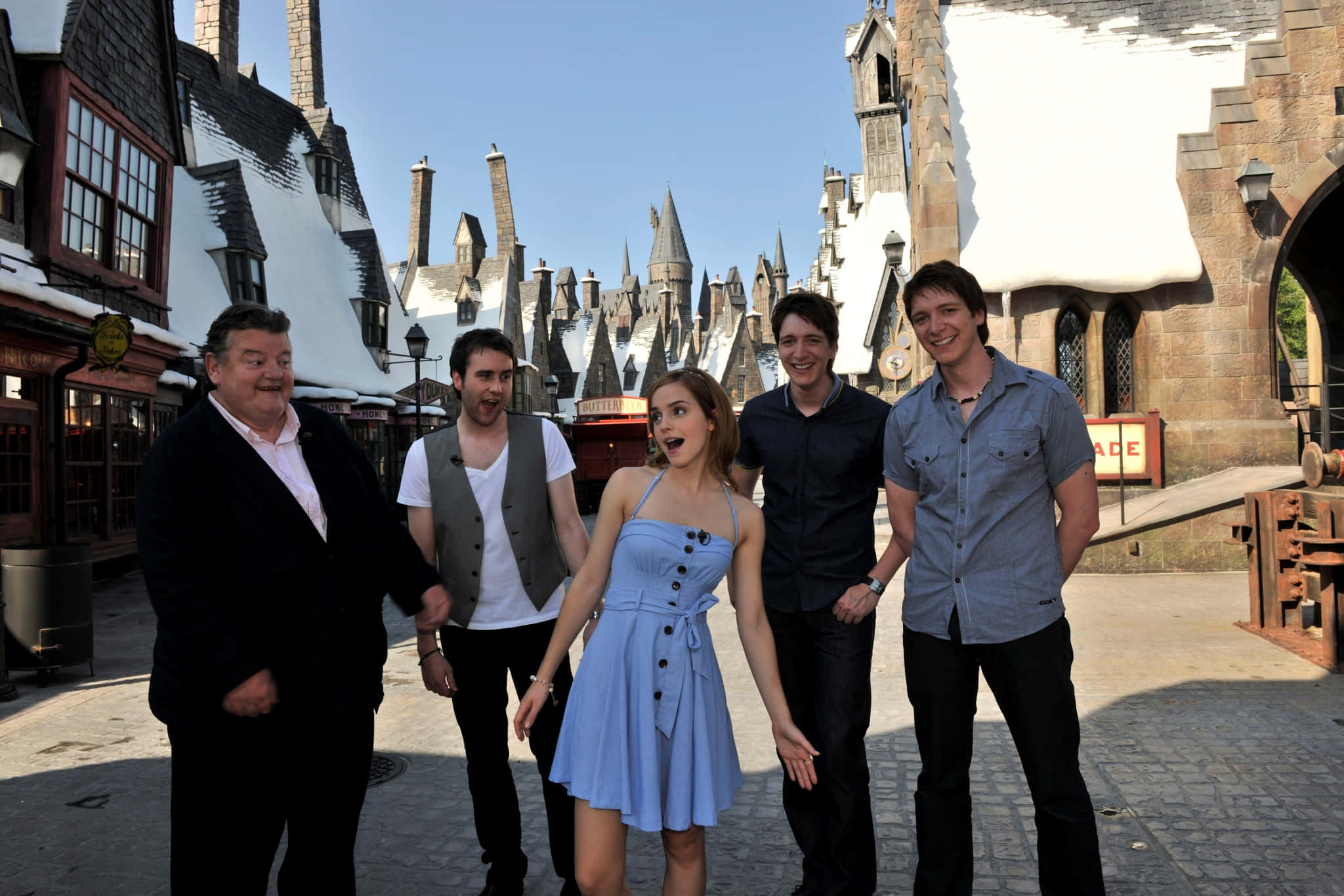Harry Potter All Characters 桌布 壁紙 — 五個人在晴朗的藍天下，愉快地在白雪覆蓋的霍格華茲城堡複製品前擺姿勢。