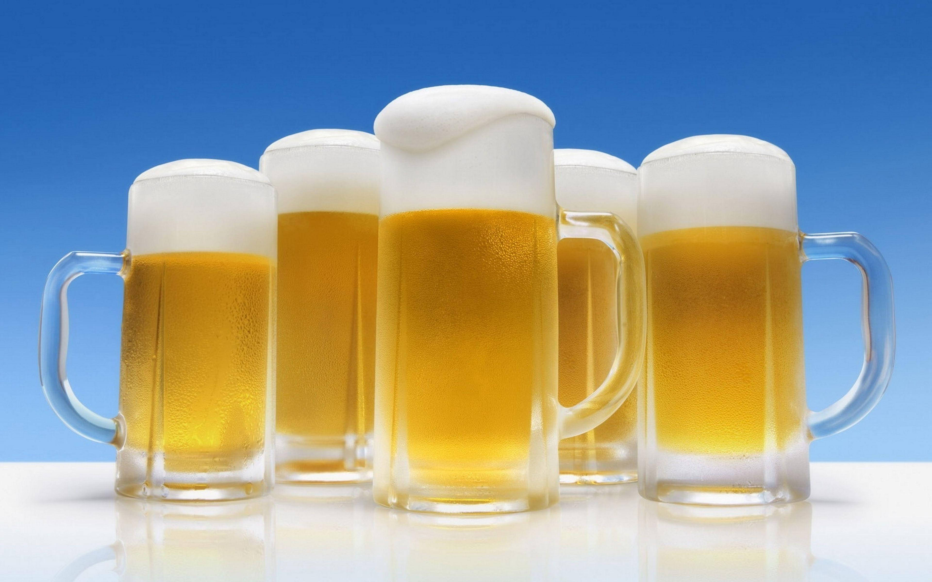 Drink 桌布 壁紙 — 五個冰凍啤酒杯，裝有金黃色液體和白色泡沫，排成一列，背景是鮮豔的藍色漸層。