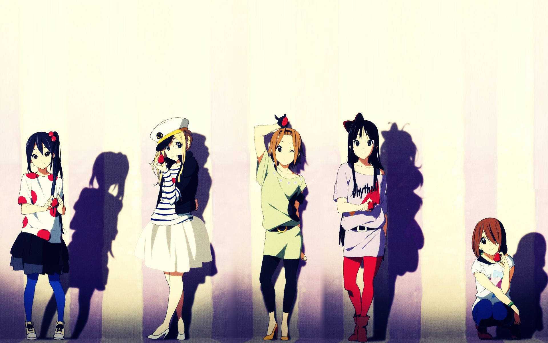 K-on 桌布 壁紙 — 五個動漫女孩穿著休閒服裝，站立和蹲在柔和照明的牆壁前，投射出長長的紫色陰影。