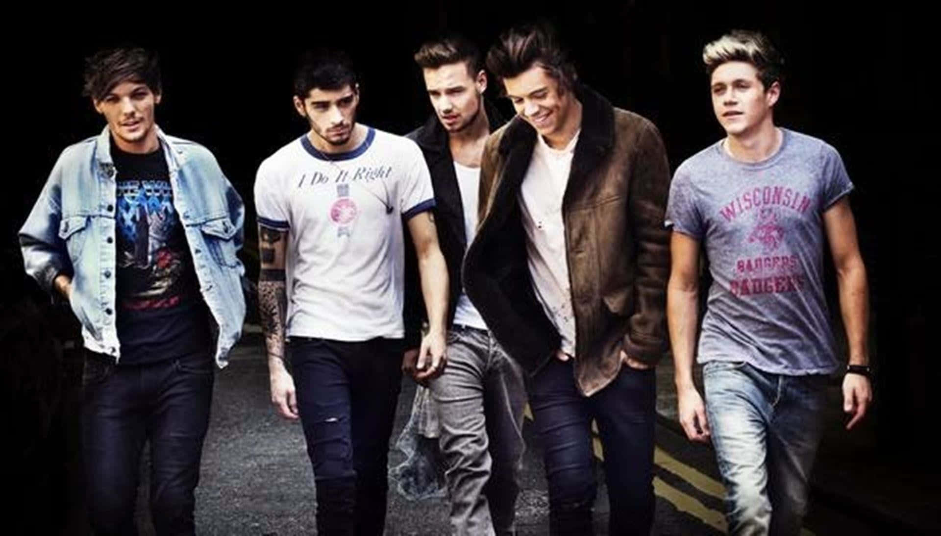 One Direction 桌布 壁紙 — 五個年輕男子穿著休閒街頭服飾，在戲劇性的燈光下自信地走下一條黑暗的城市小巷。