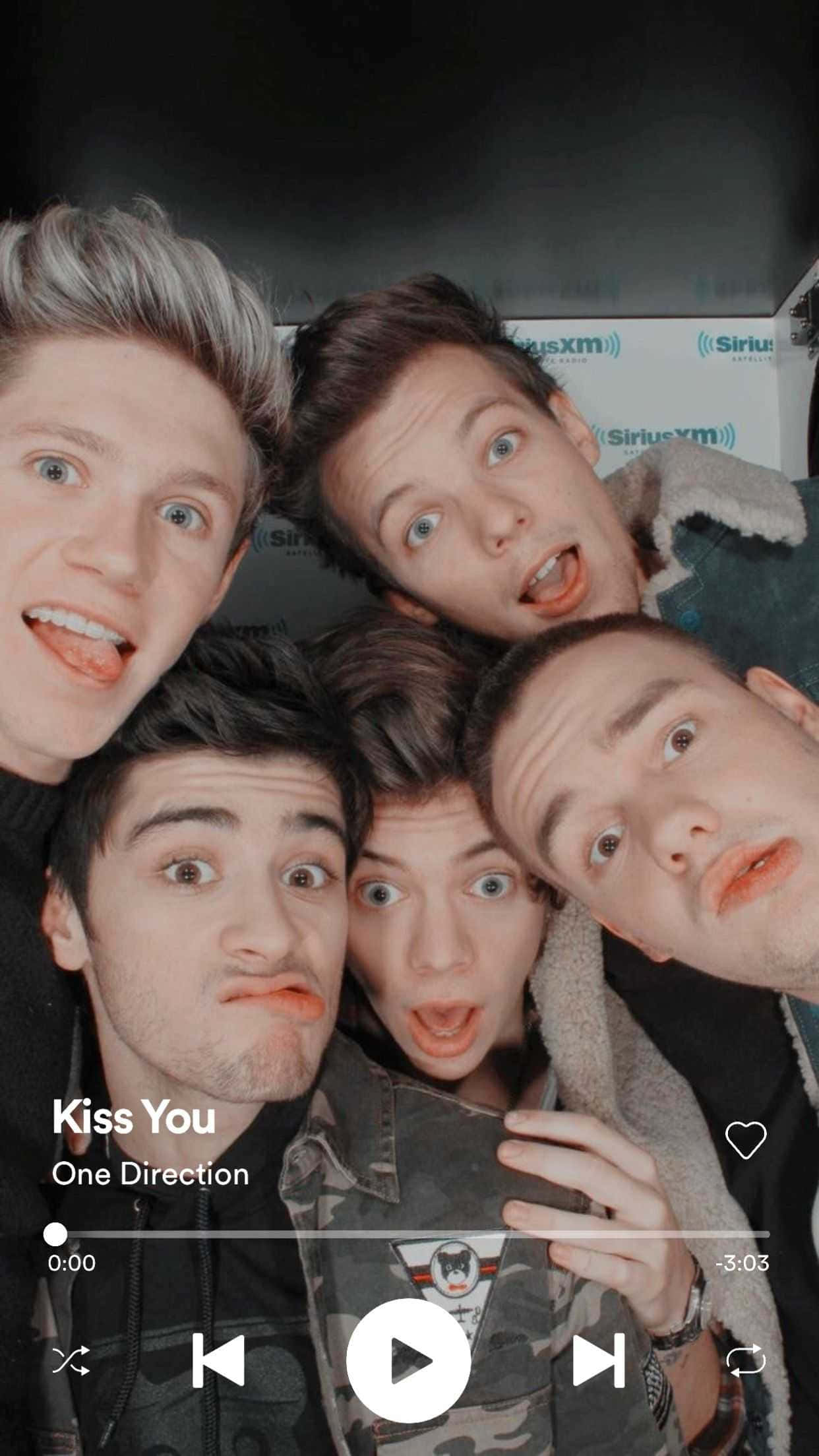 1 Direction iPhone 桌布 壁紙 — 五個年輕男子誇張地做鬼臉擠在一起自拍，上面覆蓋著One Direction的Kiss You音樂播放器介面。