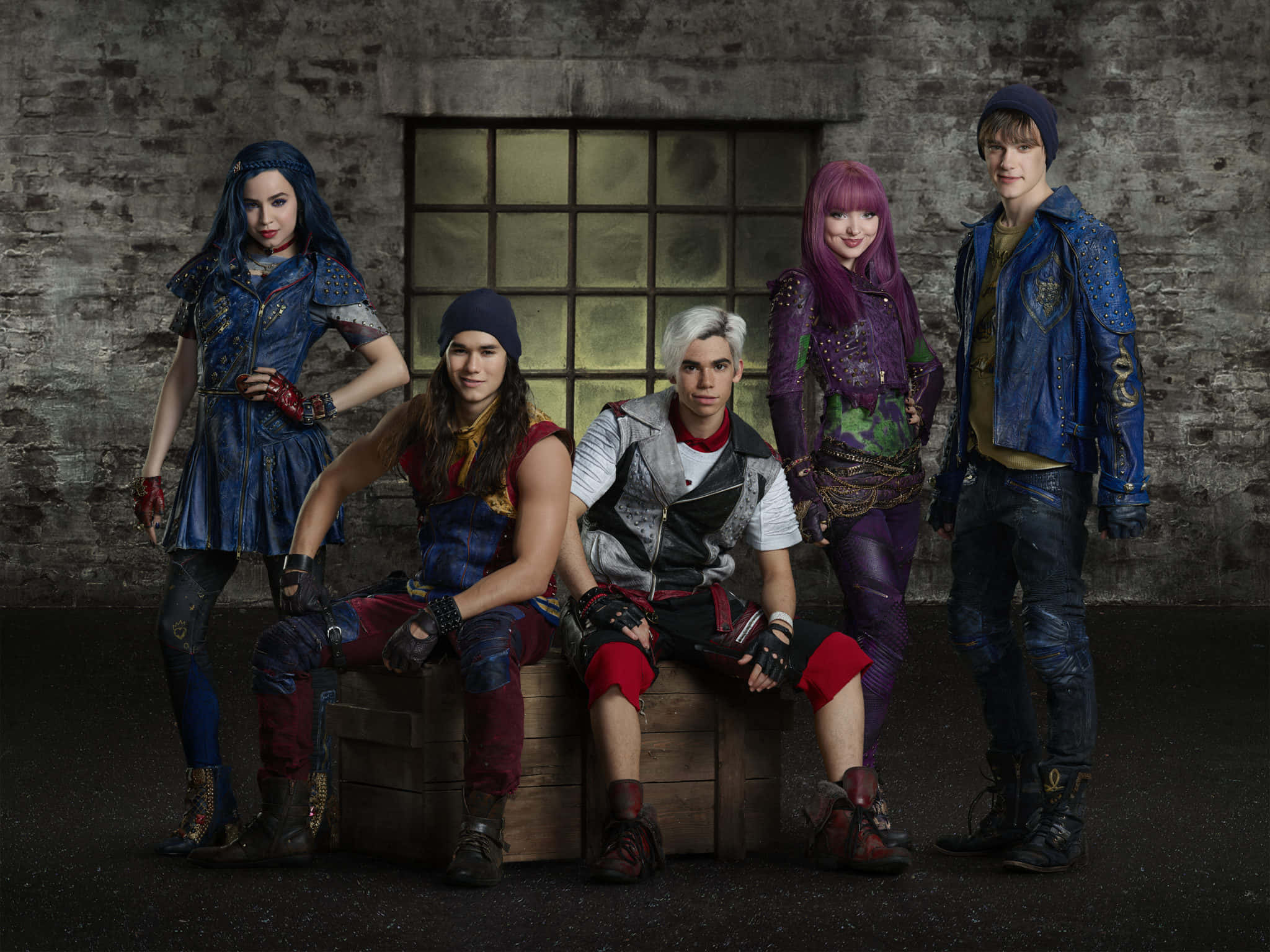 Descendants 桌布 壁紙 — 五個年輕角色穿著前衛服裝，自信地在帶有鐵窗的粗糙磚牆前擺姿勢。