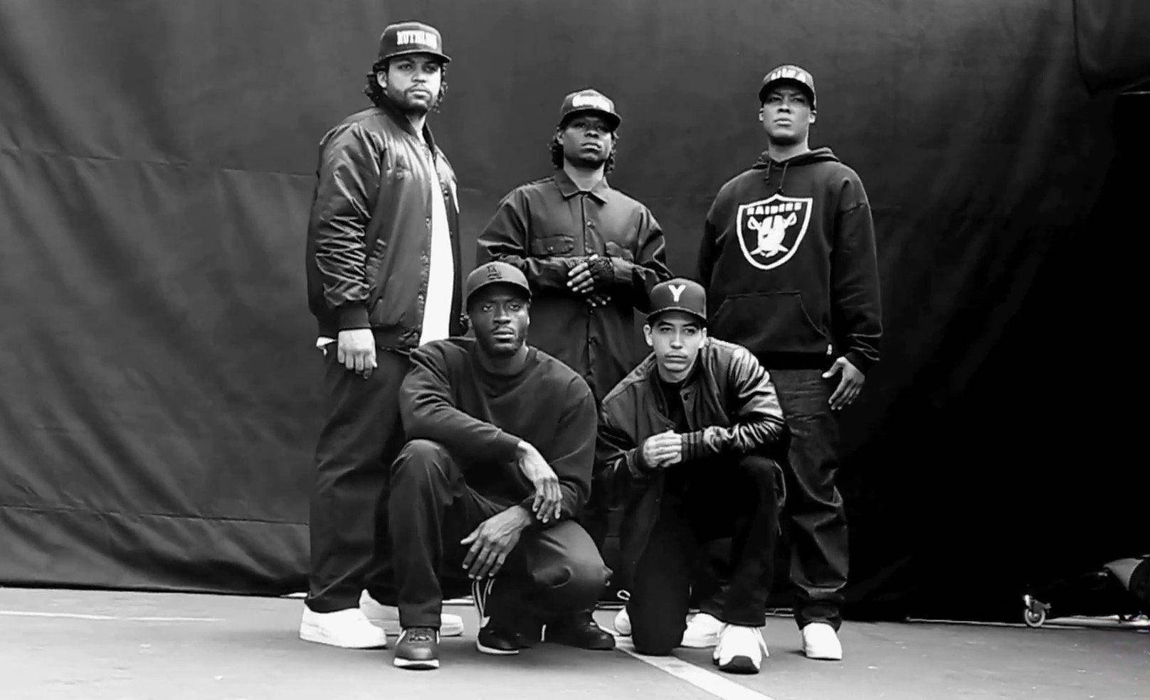 Ice Cube 桌布 壁紙 — 五個戴帽子和穿外套的男人在黑暗背景下自信地擺姿勢，拍攝成一張清晰的黑白工作室照片。