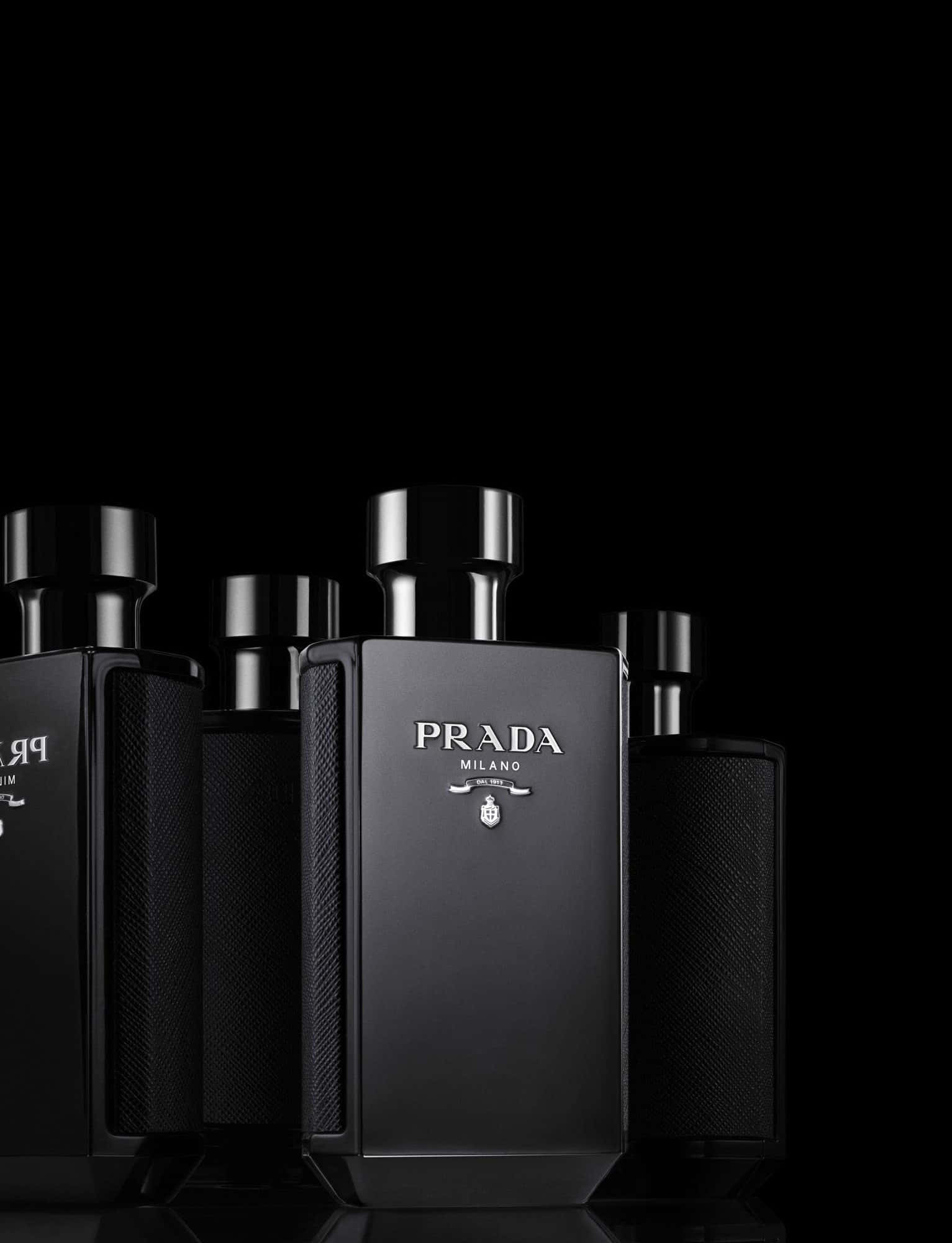 Prada 桌布 壁紙 — 五個時尚的黑色Prada Milano香水瓶排列成一行，背景為純黑色，帶有反射表面。
