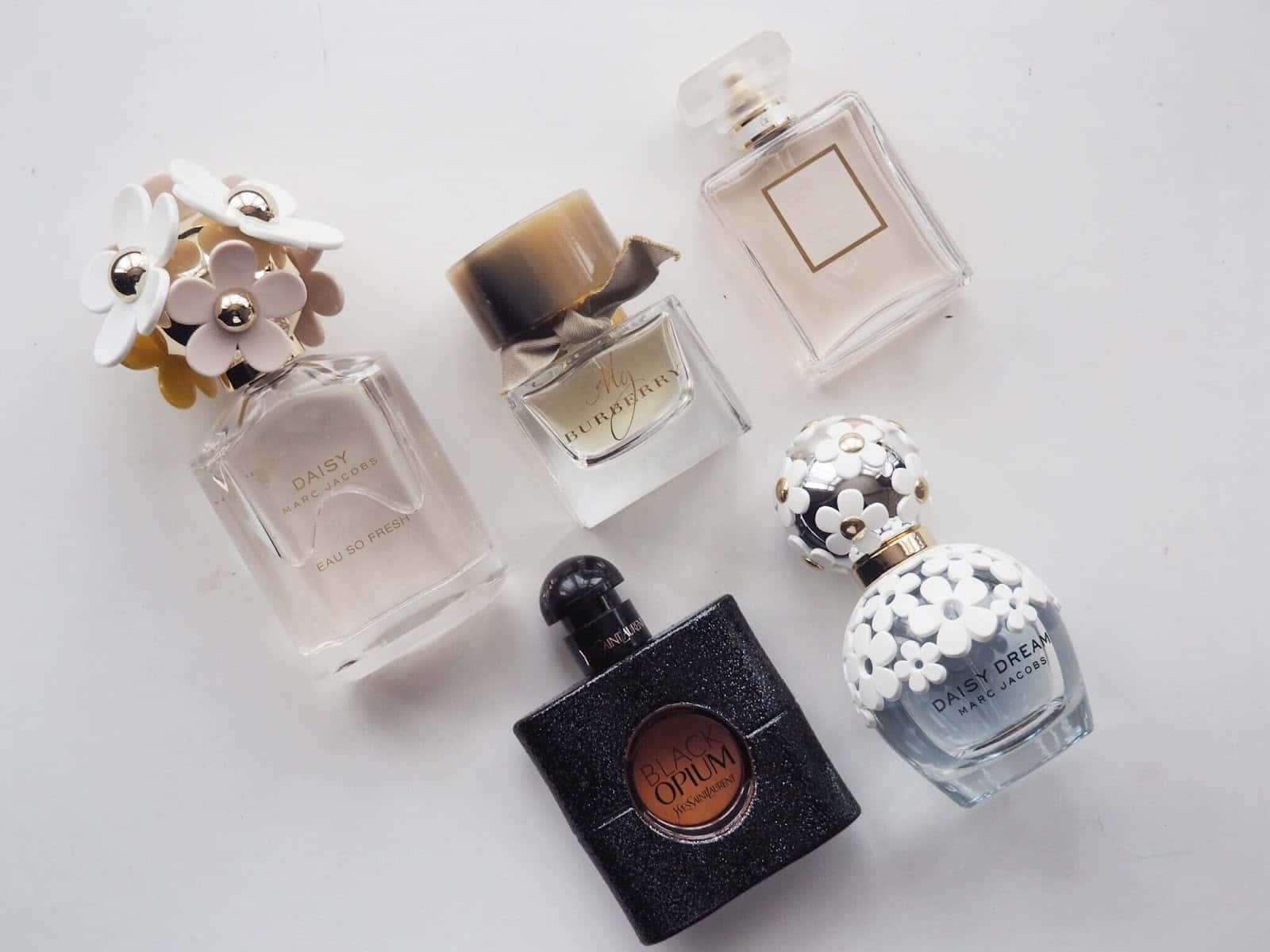 Spring Perfume 桌布 壁紙 — 五個時尚香水瓶，帶有花卉和幾何圖案設計，整齊排列在潔白的表面上。