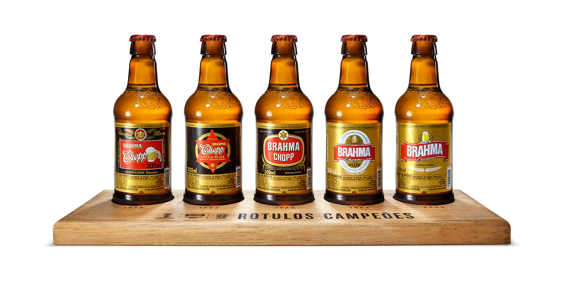 alcohol 桌布 壁紙 — 五個琥珀色的 Brahma 啤酒瓶，帶有獨特的標籤，整齊地放在一個刻有 'ROTULOS CAMPEÕES' 的木托盤上，背景是乾淨的白色。