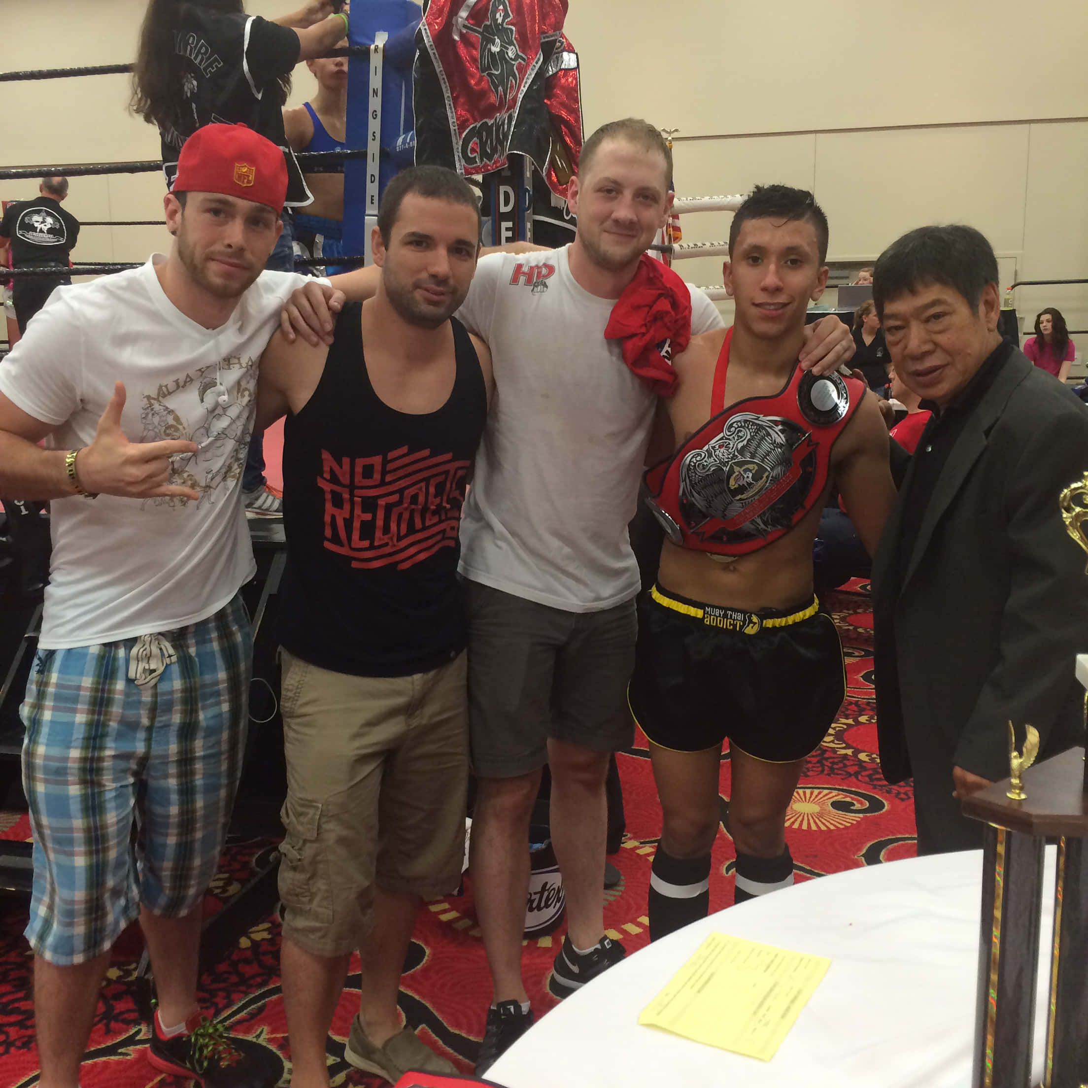 MMA 桌布 壁紙 — 五個男人一起在拳擊擂台上擺姿勢，其中一人拿著冠軍腰帶，另一人戴著紅色帽子。
