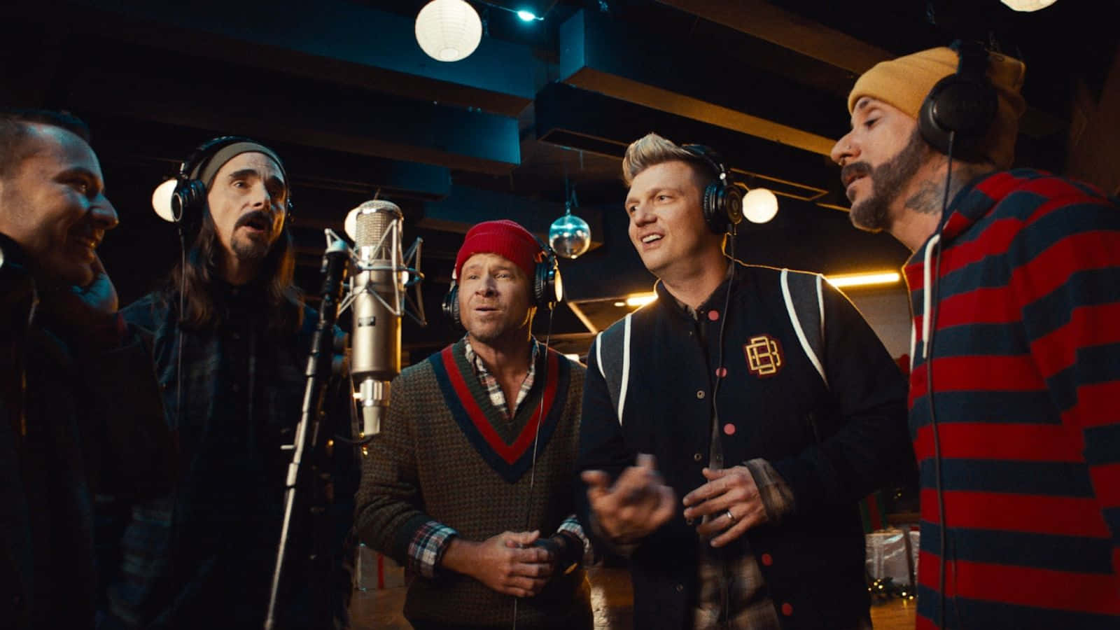 Backstreet Boys 桌布 壁紙 — 五個男人在燈光昏暗的錄音室裡戴著耳機對著麥克風唱歌，面帶微笑，投入音樂。