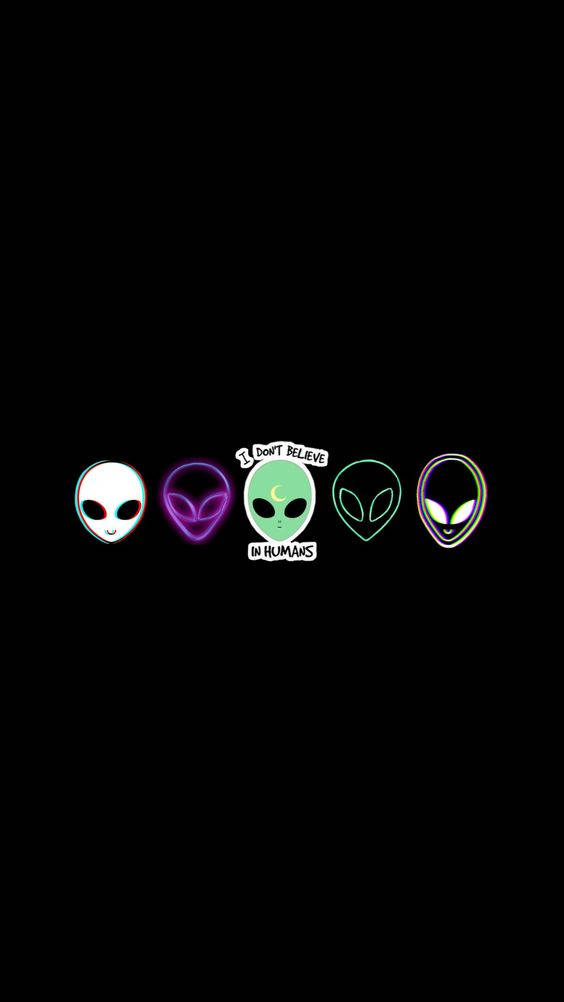 Cool Alien 桌布 壁紙 — 五個發光的外星人頭顱以霓虹色彩漂浮在黑色背景上，中央一個綠色外星人舉著寫有「I DON'T BELIEVE IN HUMANS」的牌子。