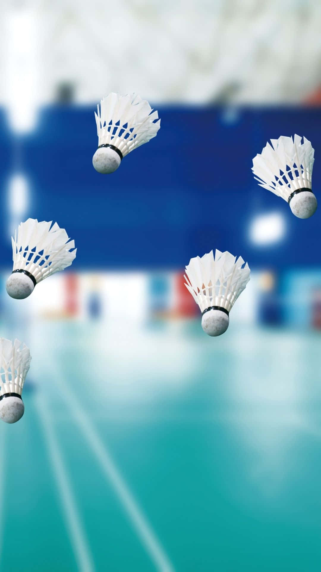 Shuttlecock 桌布 壁紙 — 五個白色羽毛球在半空中飛翔，背景是模糊的羽毛球場，有藍色牆壁和綠色地板。