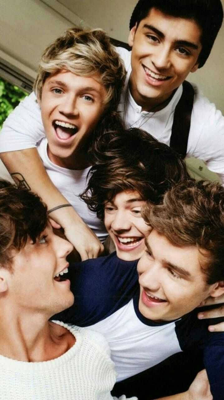 One Direction Aesthetic 桌布 壁紙 — 五個穿著休閒服的年輕男子擠在一起，大笑並露出燦爛的笑容，緊緊地擁抱成一團。