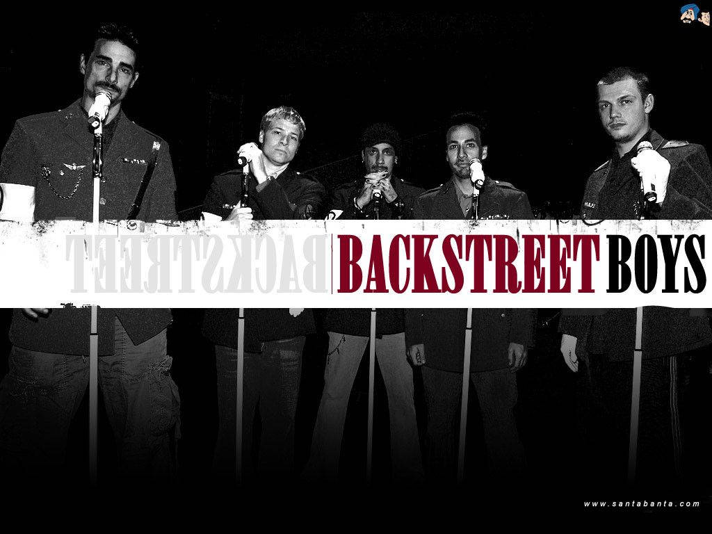 Backstreet 桌布 壁紙 — 五個穿著深色外套的男人站在麥克風後面，在戲劇性的黑白燈光下，中間有一條大膽的紅色和黑色「BACKSTREET BOYS」橫幅。