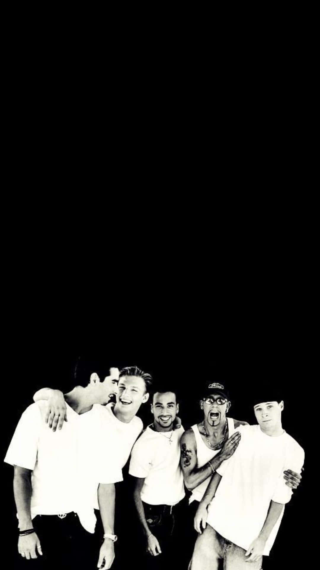Backstreet Boys 桌布 壁紙 — 五個穿著白襯衫的男人在黑色背景前大笑並擺姿勢，高對比度的黑白照片。