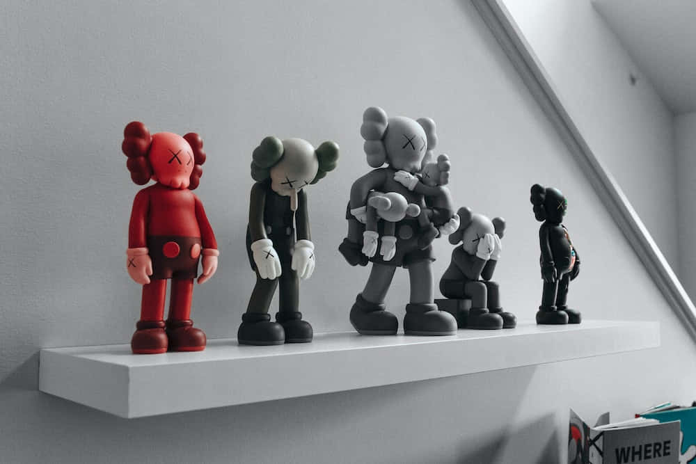 KAWS 桌布 壁紙 — 五個紅色、灰色和黑色的KAWS公仔站在白色層架上，背景是簡約的灰色牆壁。