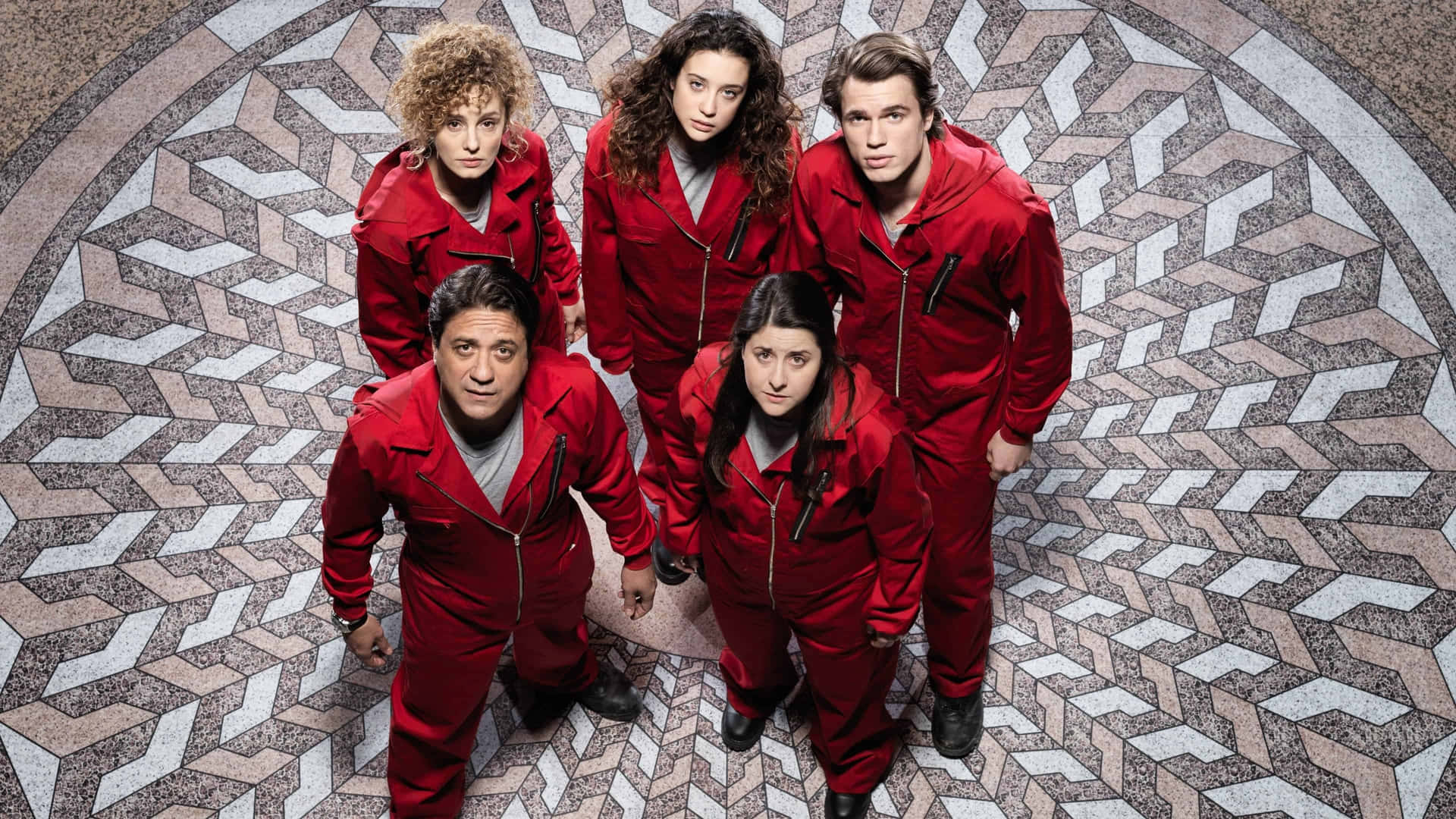 Money Heist Mask 桌布 壁紙 — 五個身穿相同紅色連身工作服的人從幾何圖案地板向上凝視。