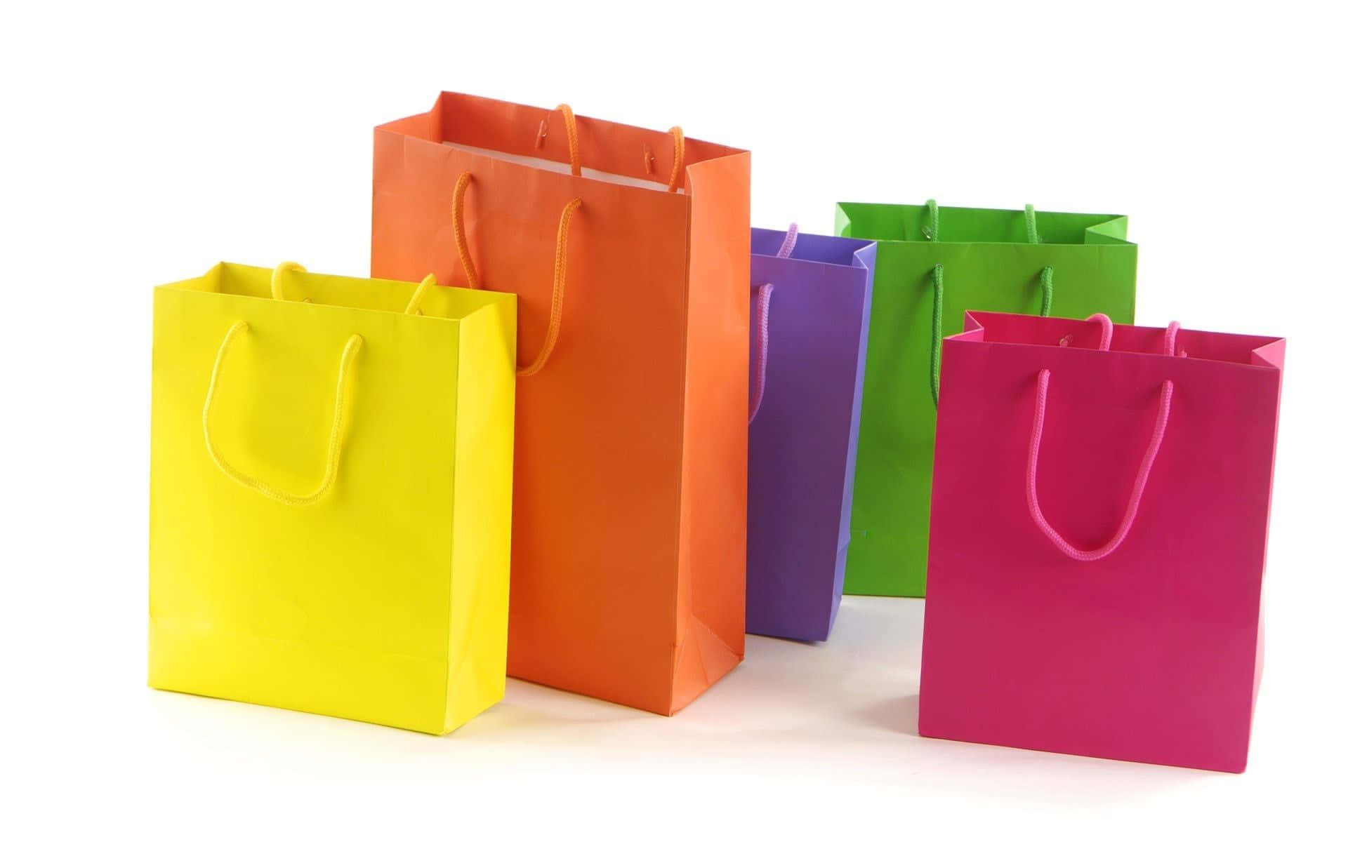 Shopping 桌布 壁紙 — 五個顏色鮮豔的購物袋，分別是黃色、橙色、紫色、綠色和粉紅色，立在潔白的背景上。