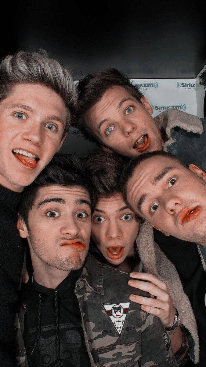 One Direction Aesthetic 桌布 壁紙 — 五名年輕男子睜大眼睛、嘴唇帶橙調，在SiriusXM背景下緊密擺姿勢拍攝俏皮自拍。
