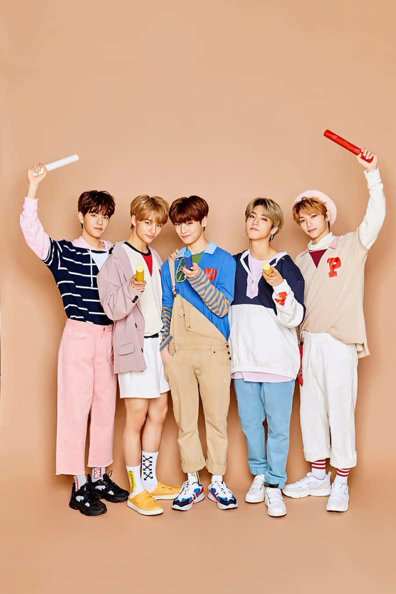 Stray Kids 2020 桌布 壁紙 — 五名年輕男子身穿色彩繽紛的休閒服裝，在純色蜜桃色背景前開心地擺姿勢，手持糖果和螢光棒。