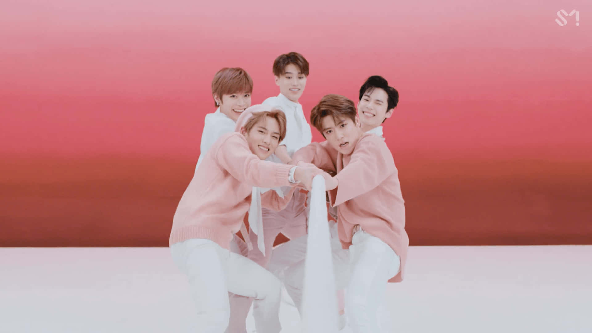 Cute Kpop 桌布 壁紙 — 五名微笑的年輕男子穿著粉紅色毛衣，在紅色漸變背景前一起擺姿勢。